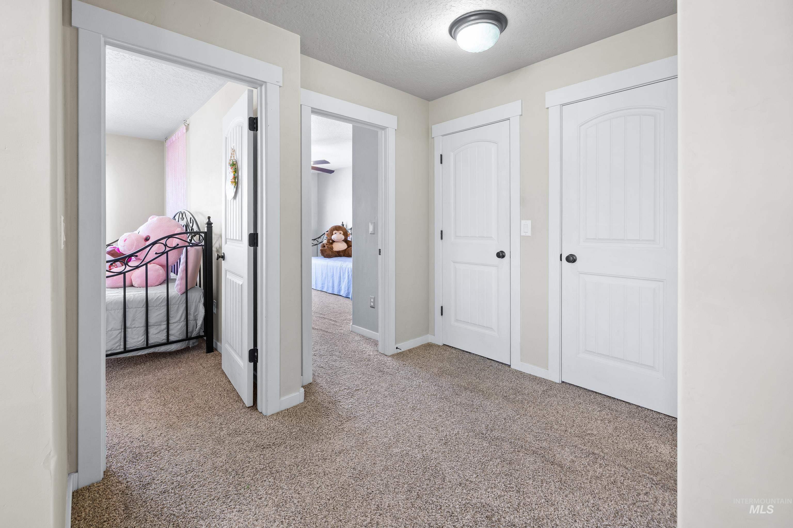Corridor featuring a textured ceiling and light colored carpet