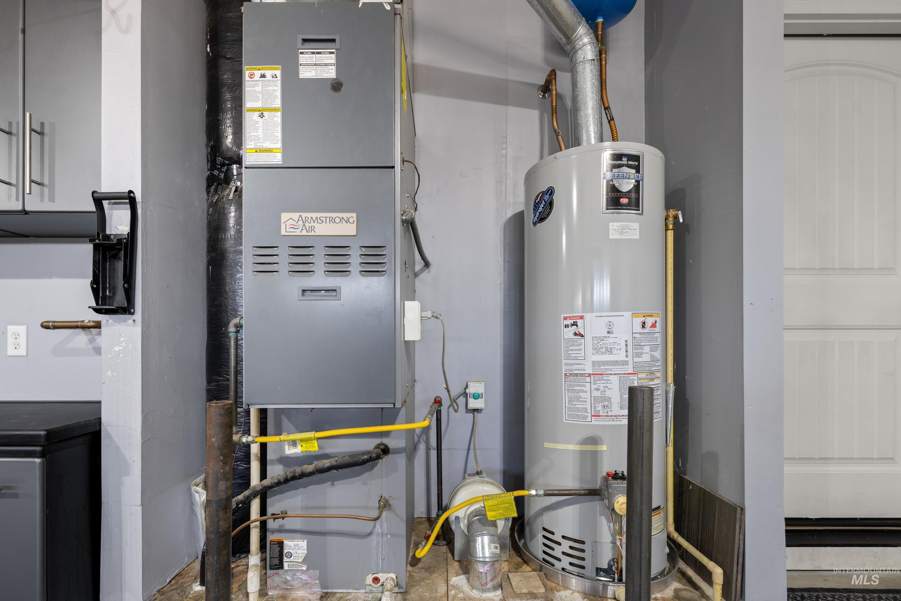 Utility room featuring heating unit and gas water heater