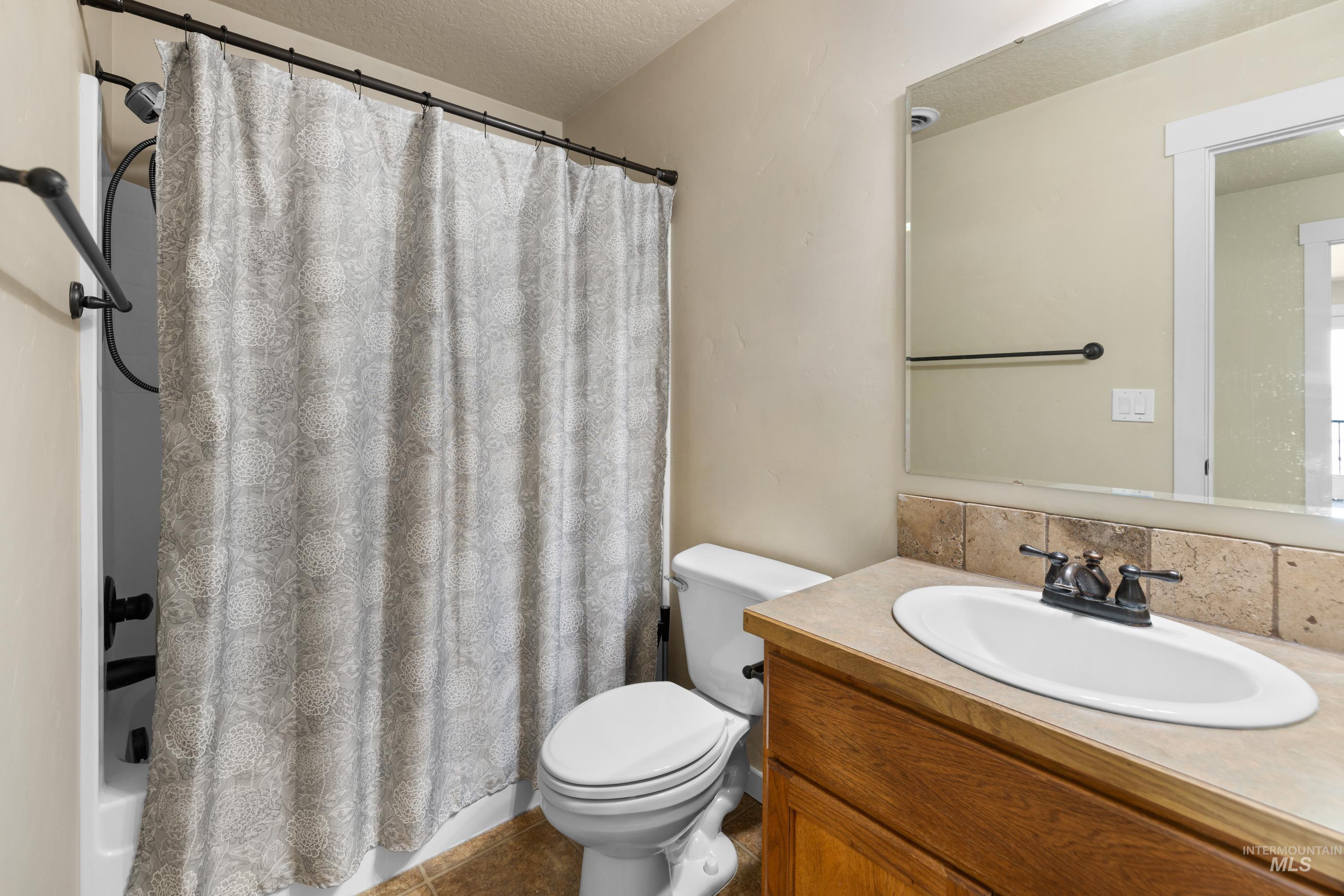 Bathroom featuring vanity, a textured ceiling, and shower / tub combo