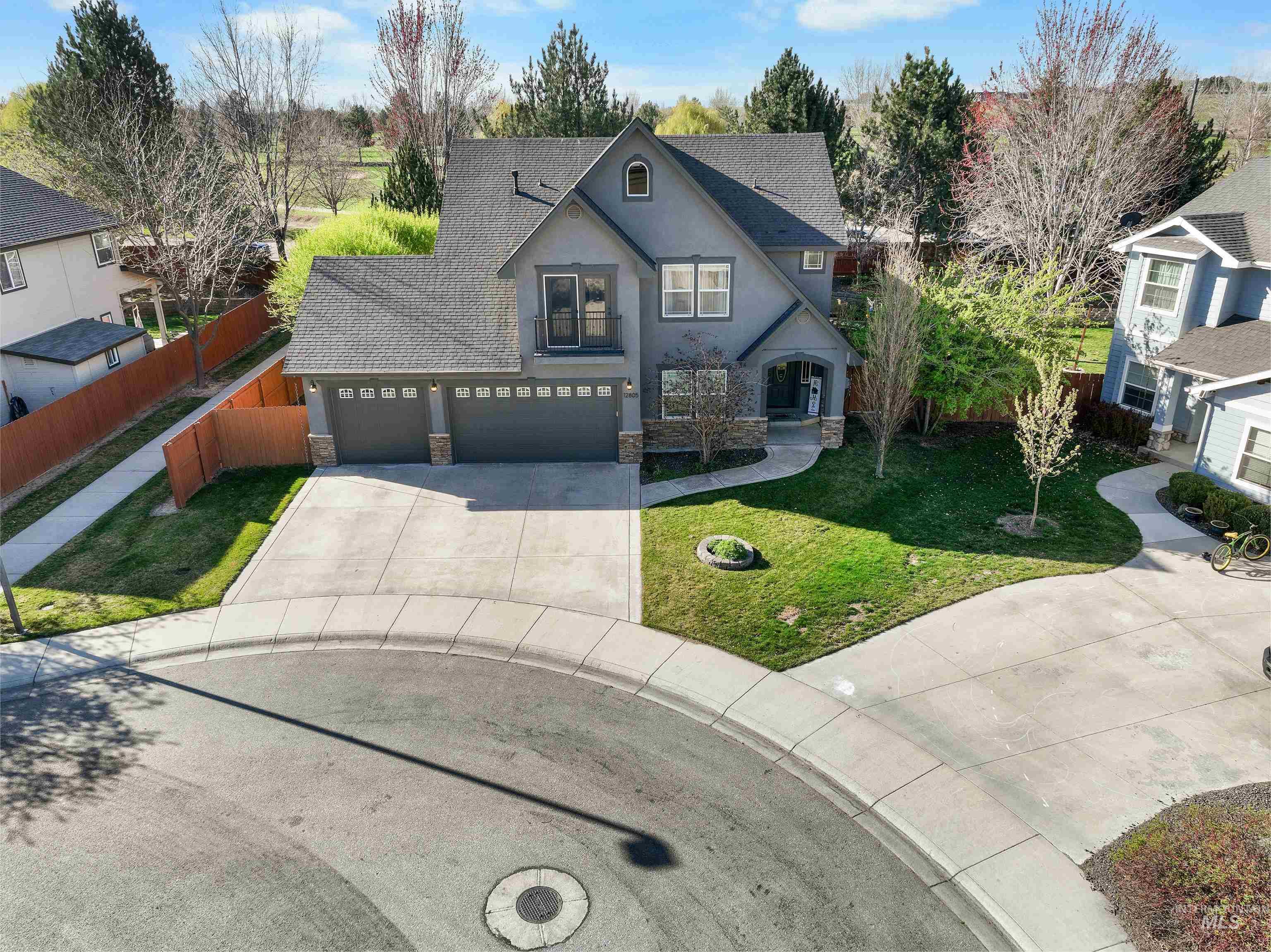 View of front of home featuring stone siding, roof with shingles, concrete driveway, and stucco siding