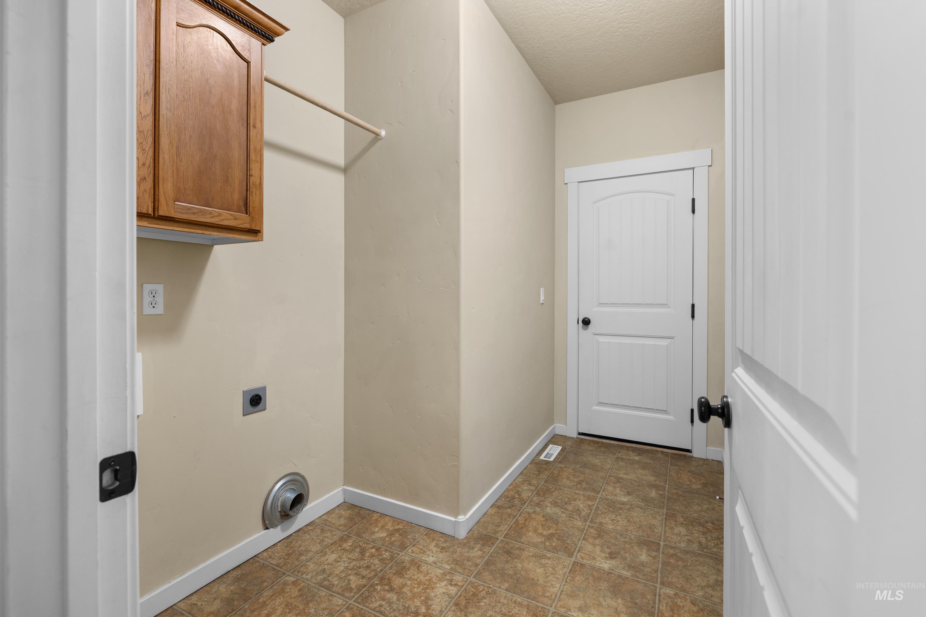 Laundry area featuring cabinet space, a textured ceiling, and hookup for an electric dryer