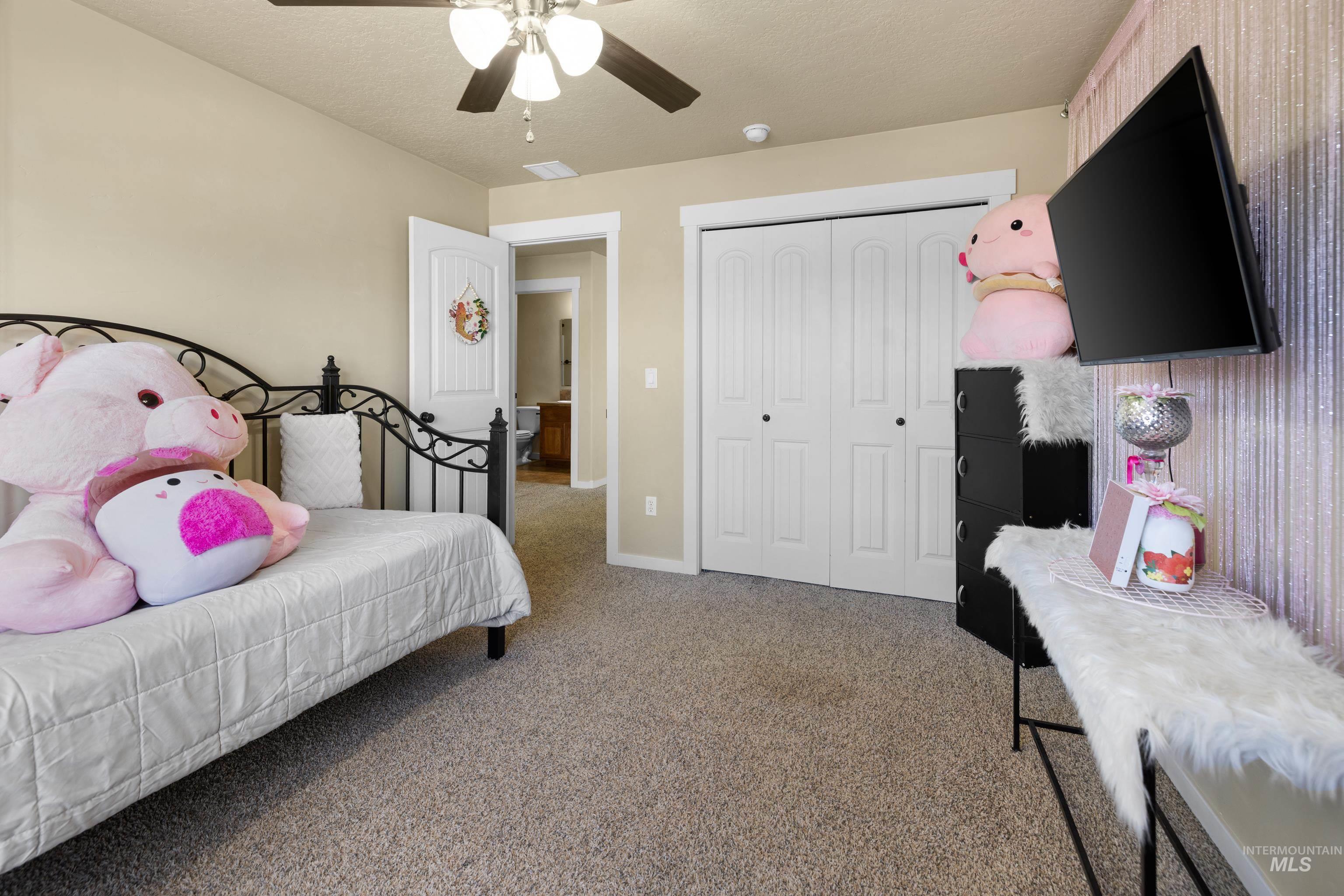 Bedroom with light colored carpet, a closet, ceiling fan, and a textured ceiling