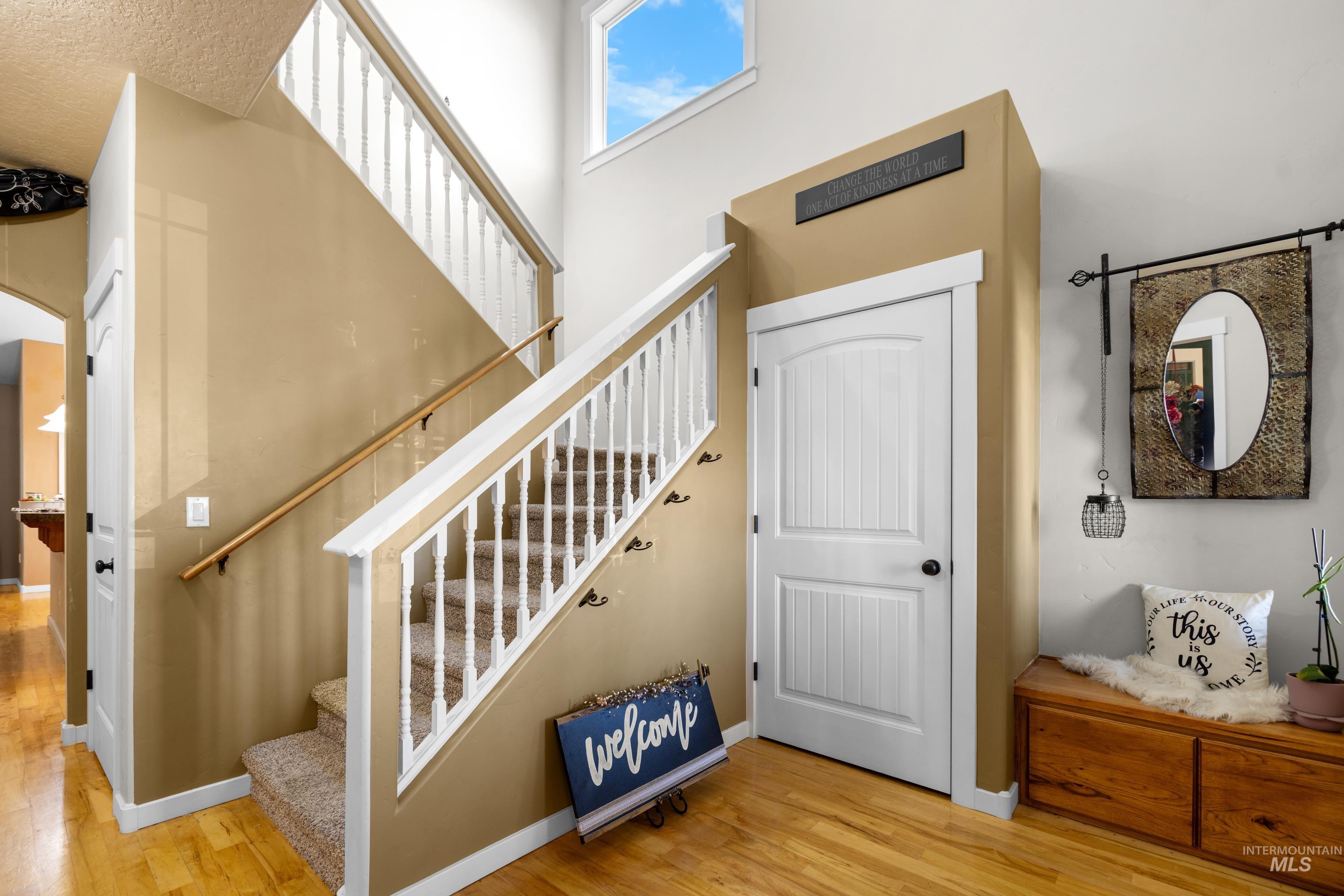 Staircase featuring wood finished floors, a high ceiling, and arched walkways