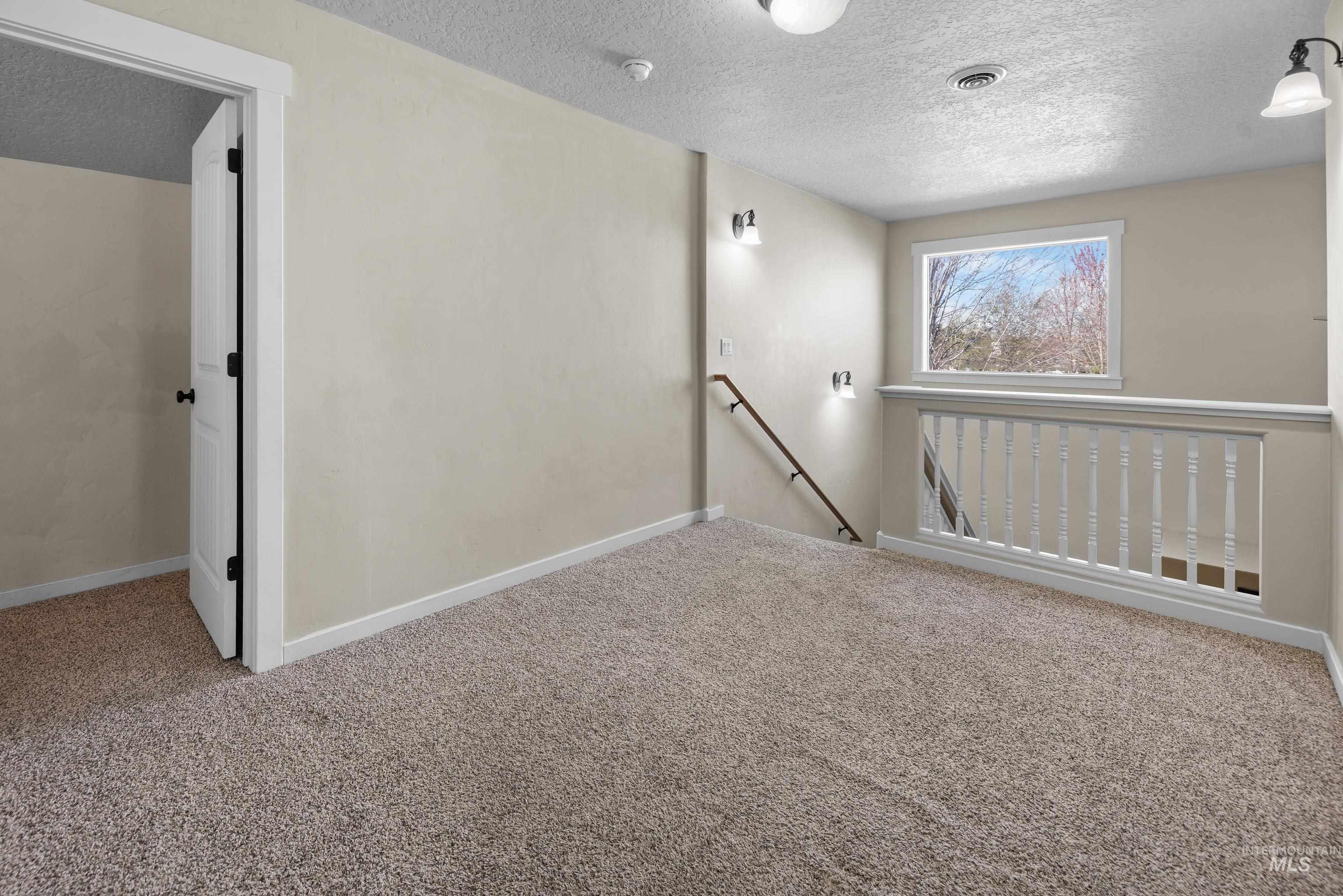 Unfurnished room featuring carpet flooring and a textured ceiling