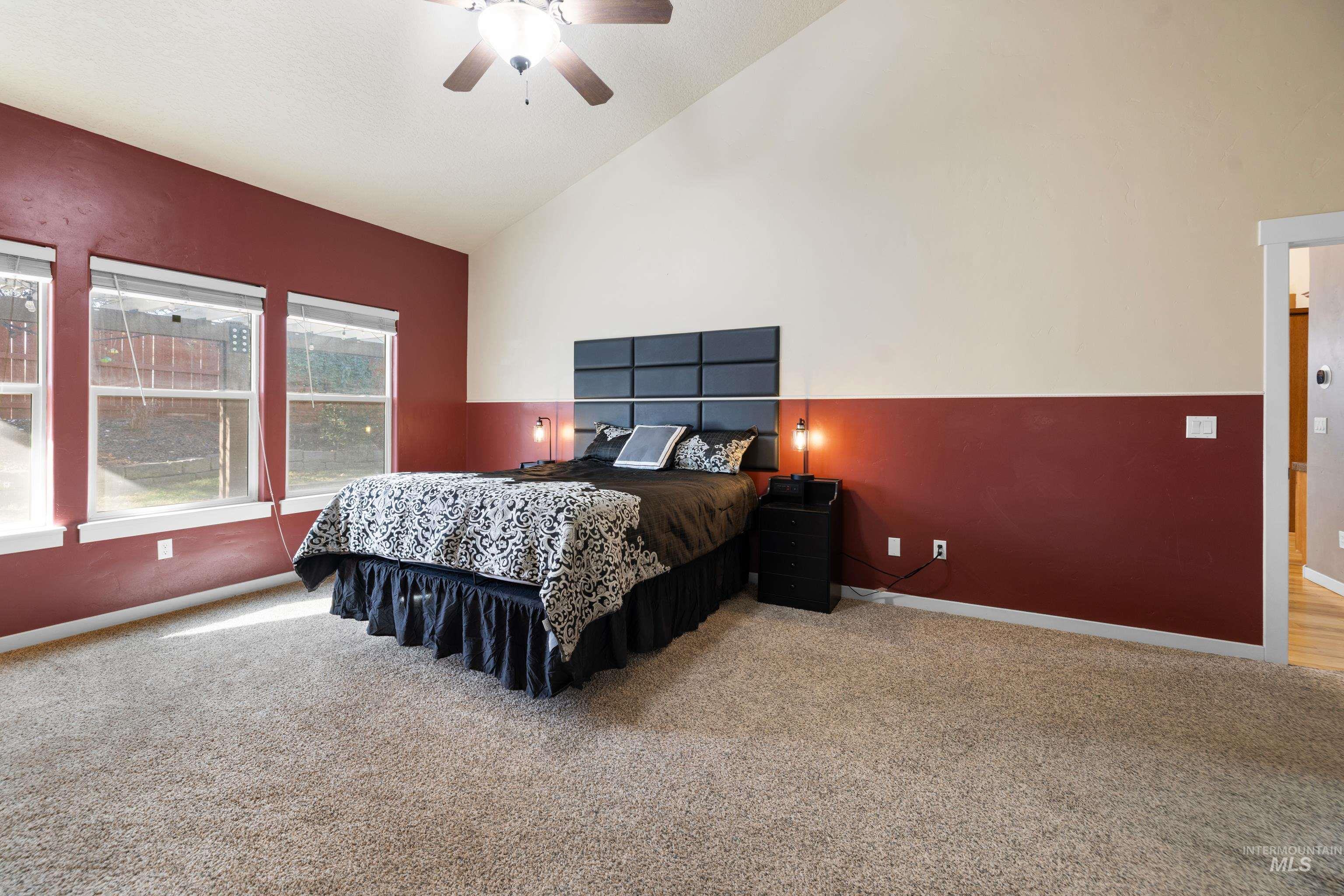 Carpeted bedroom with lofted ceiling and ceiling fan
