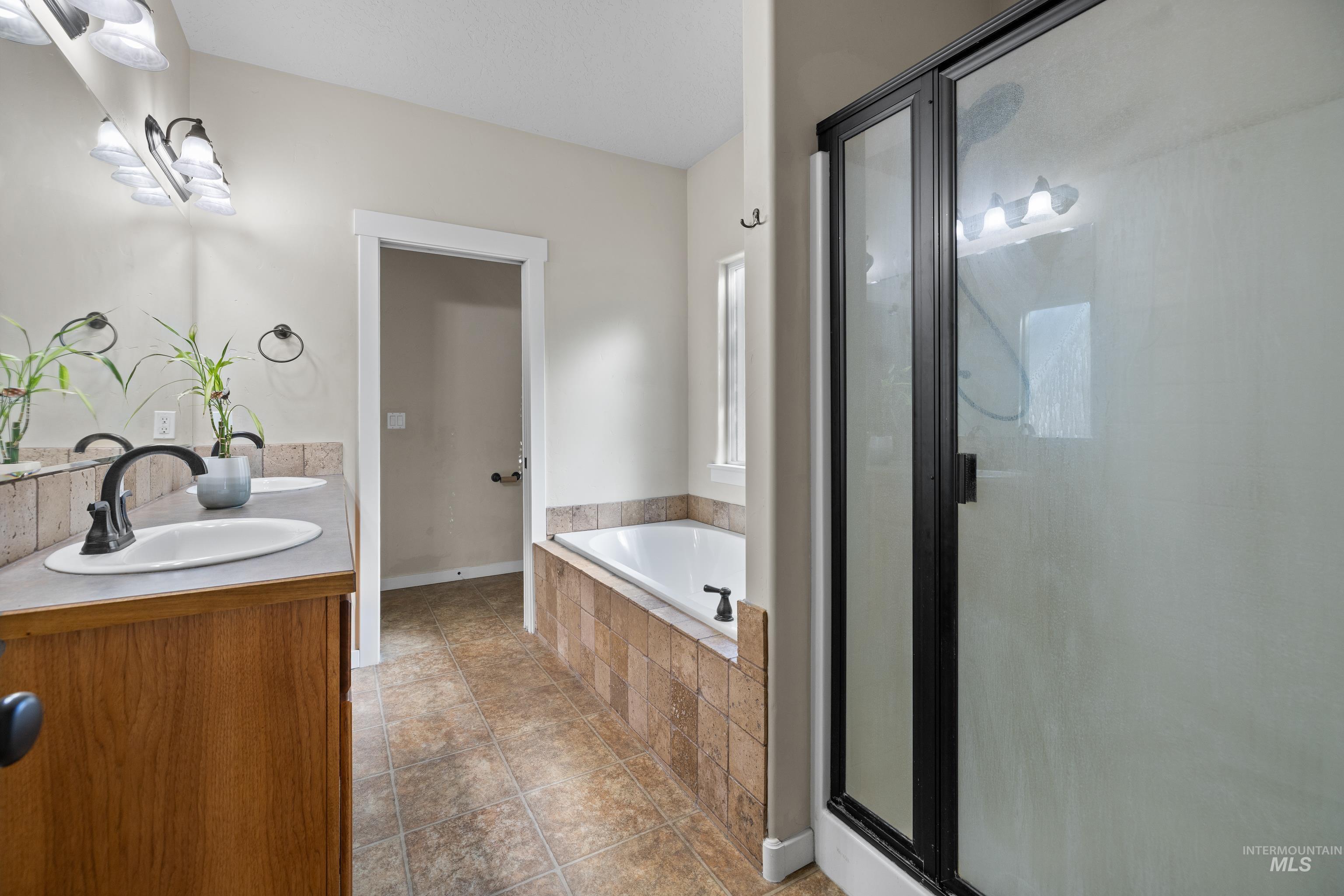 Bathroom featuring double vanity, a garden tub, and a shower stall