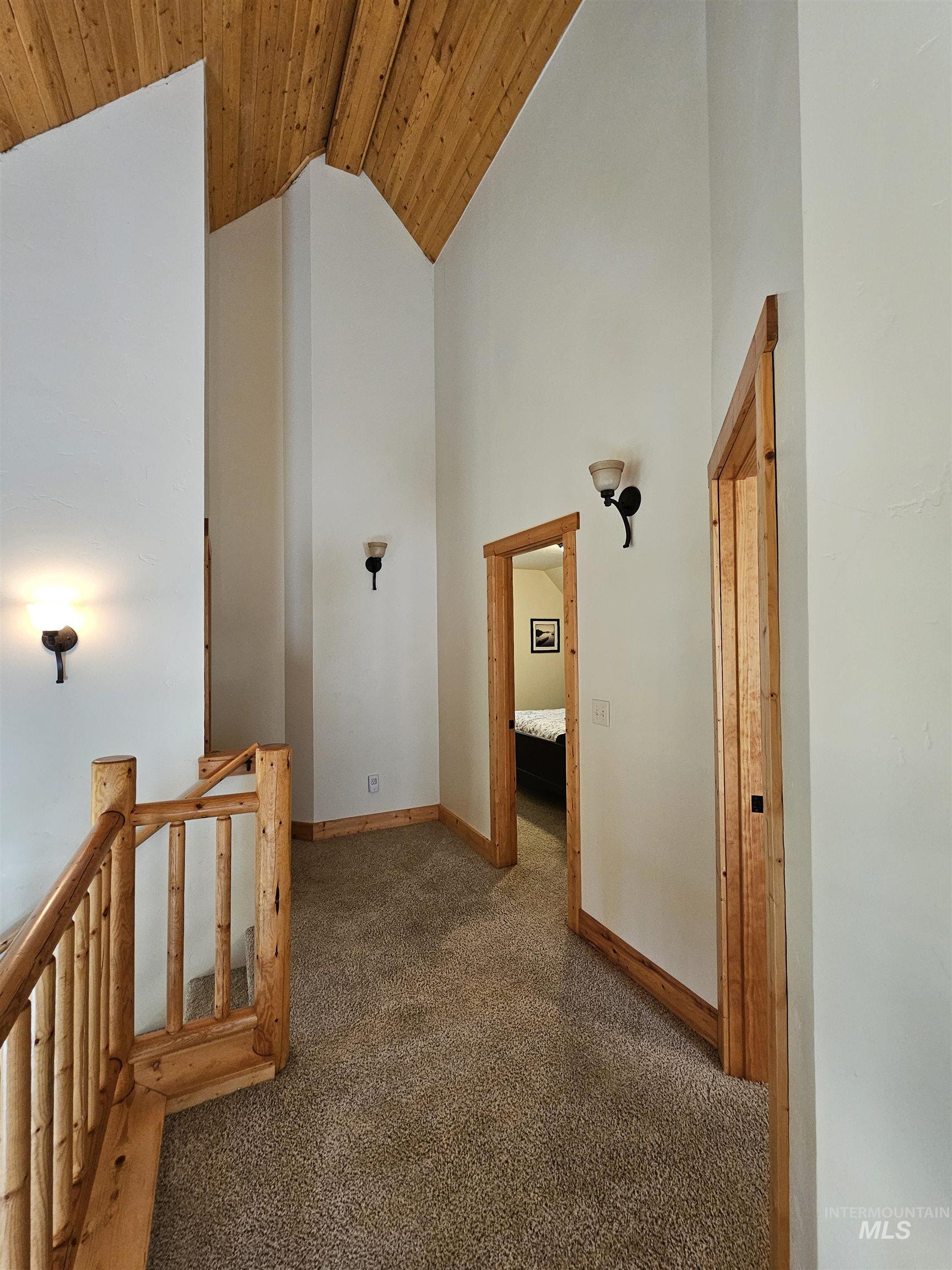 Corridor featuring carpet floors, high vaulted ceiling, wooden ceiling, and an upstairs landing