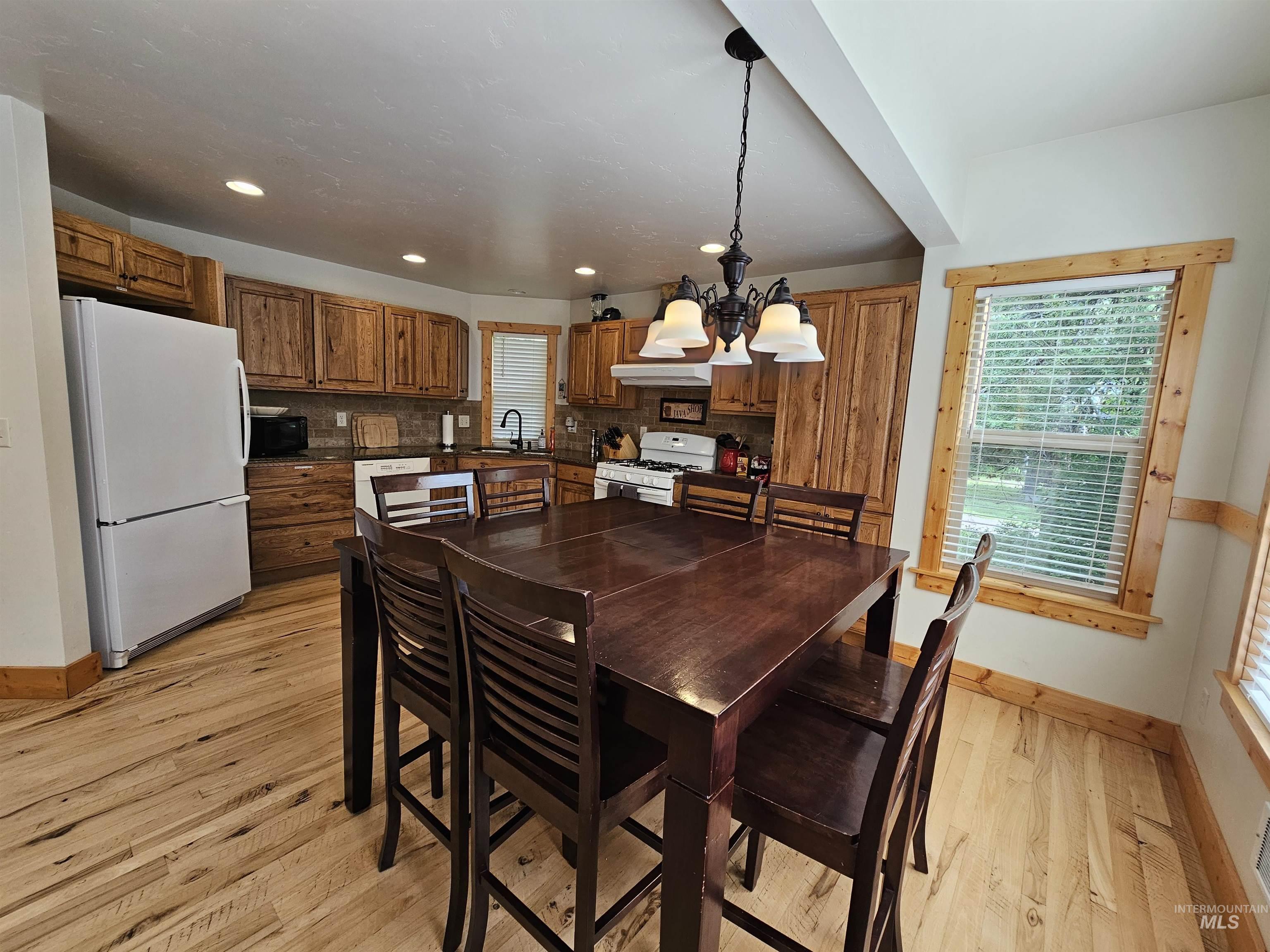 Dining area featuring light wood-style floors, recessed lighting, and a chandelier