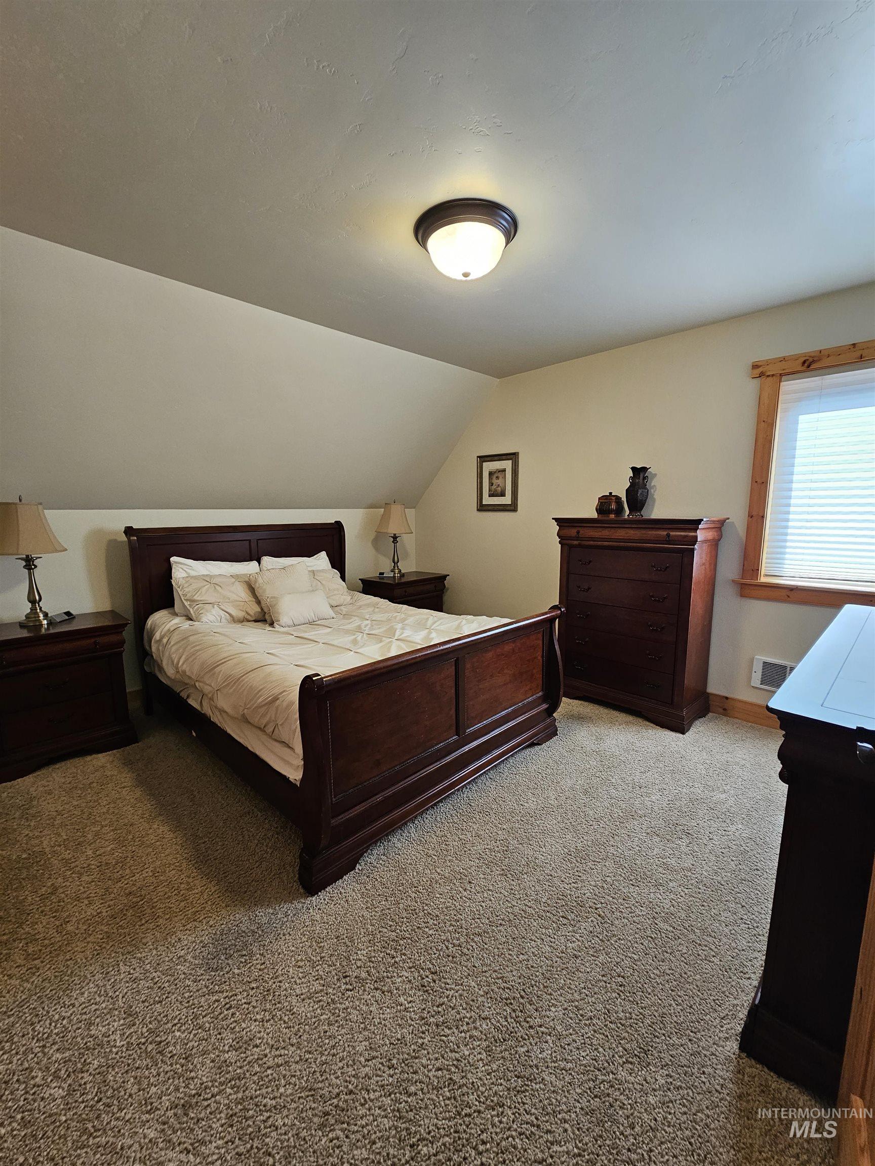 Bedroom featuring carpet flooring and vaulted ceiling