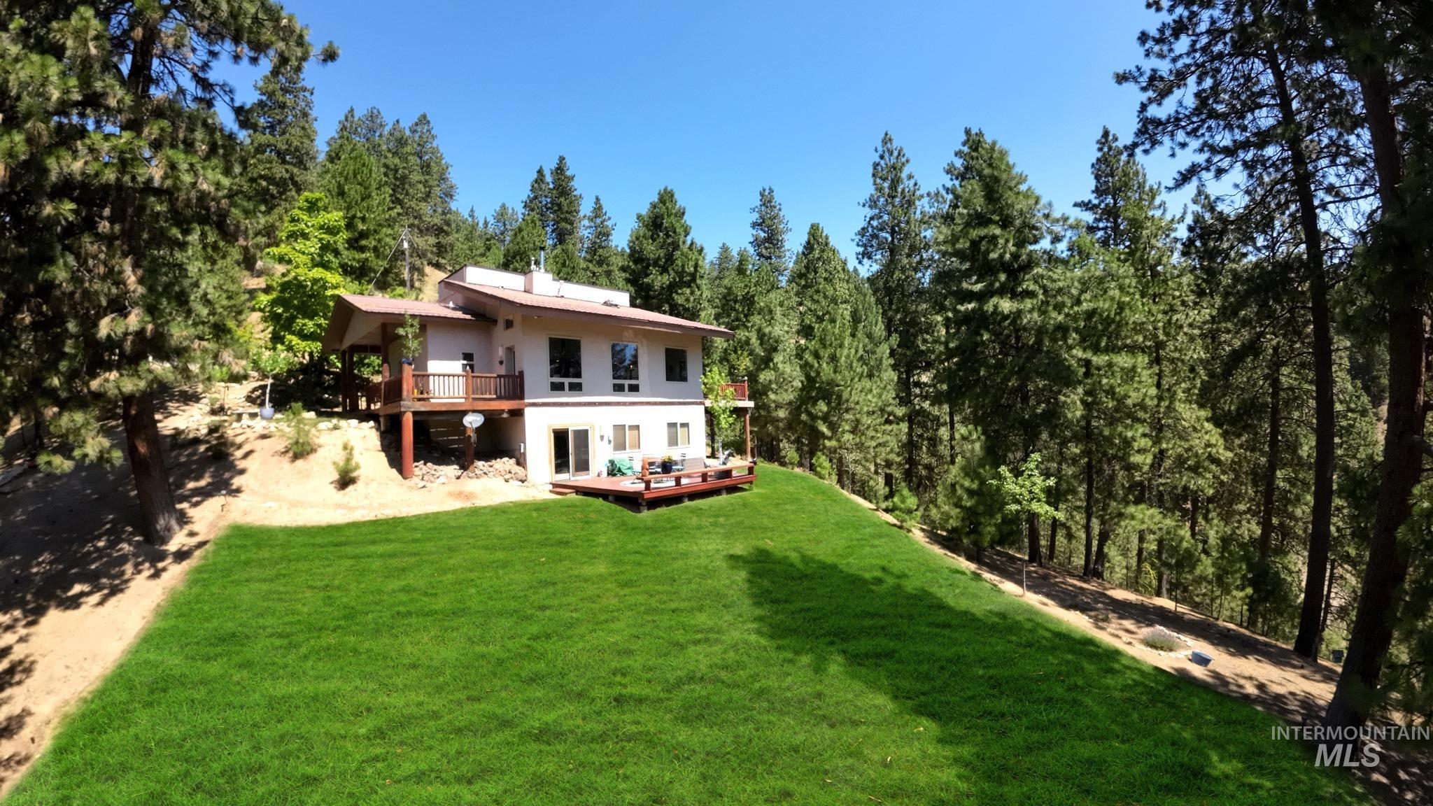 Back of house with a deck, a yard, a view of trees, and stucco siding