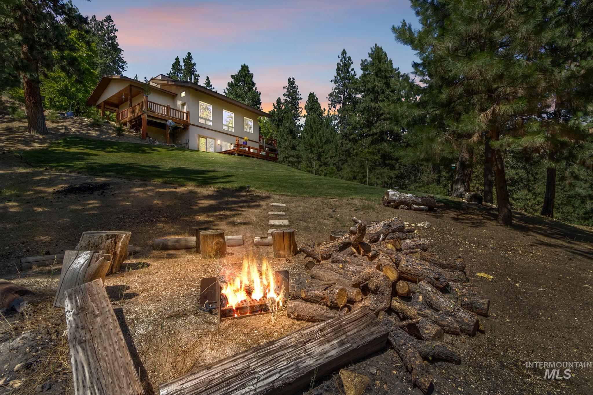 Yard at dusk with a fire pit, a lawn, and a deck