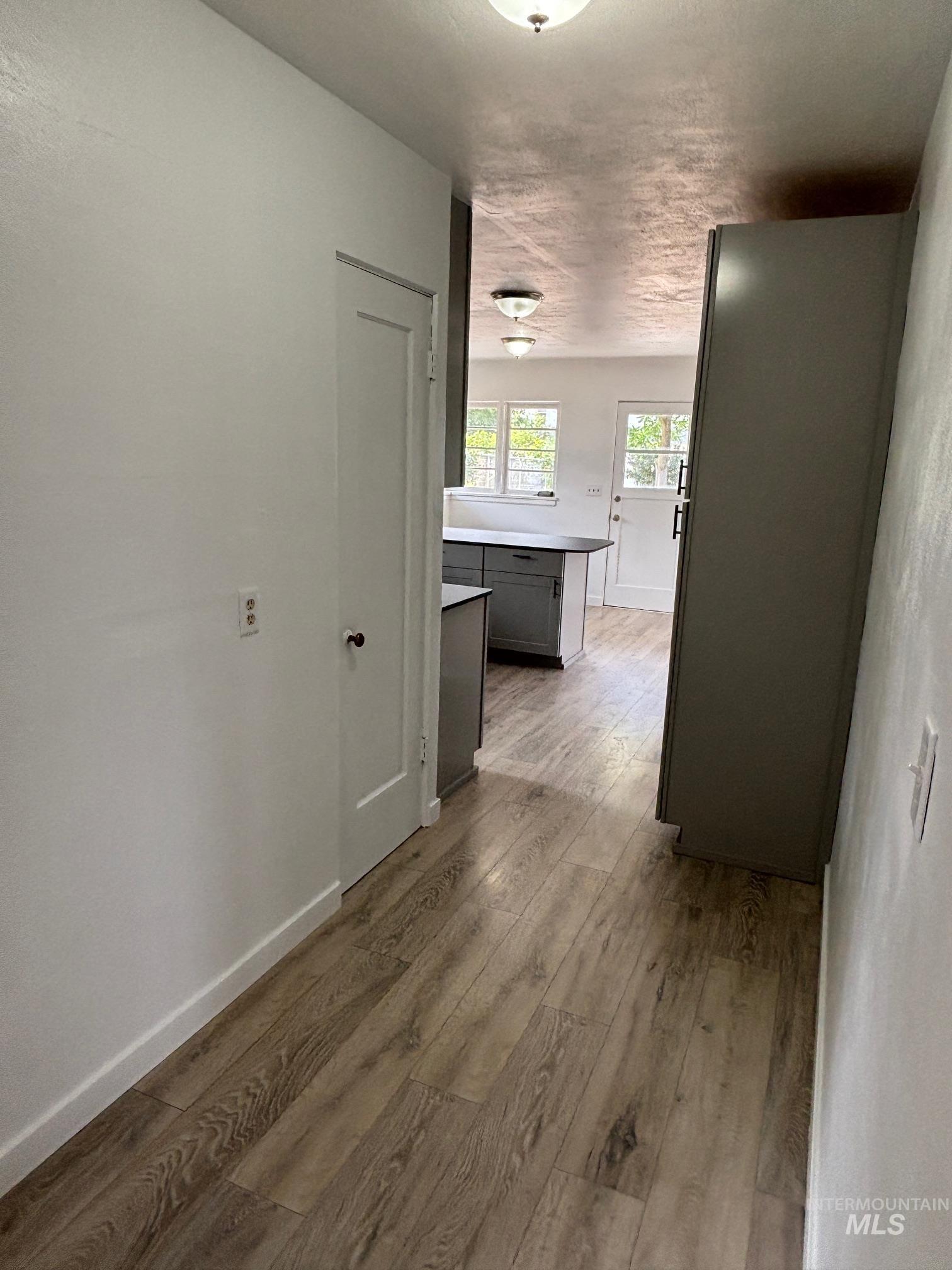 Hall with light wood-type flooring and a textured ceiling