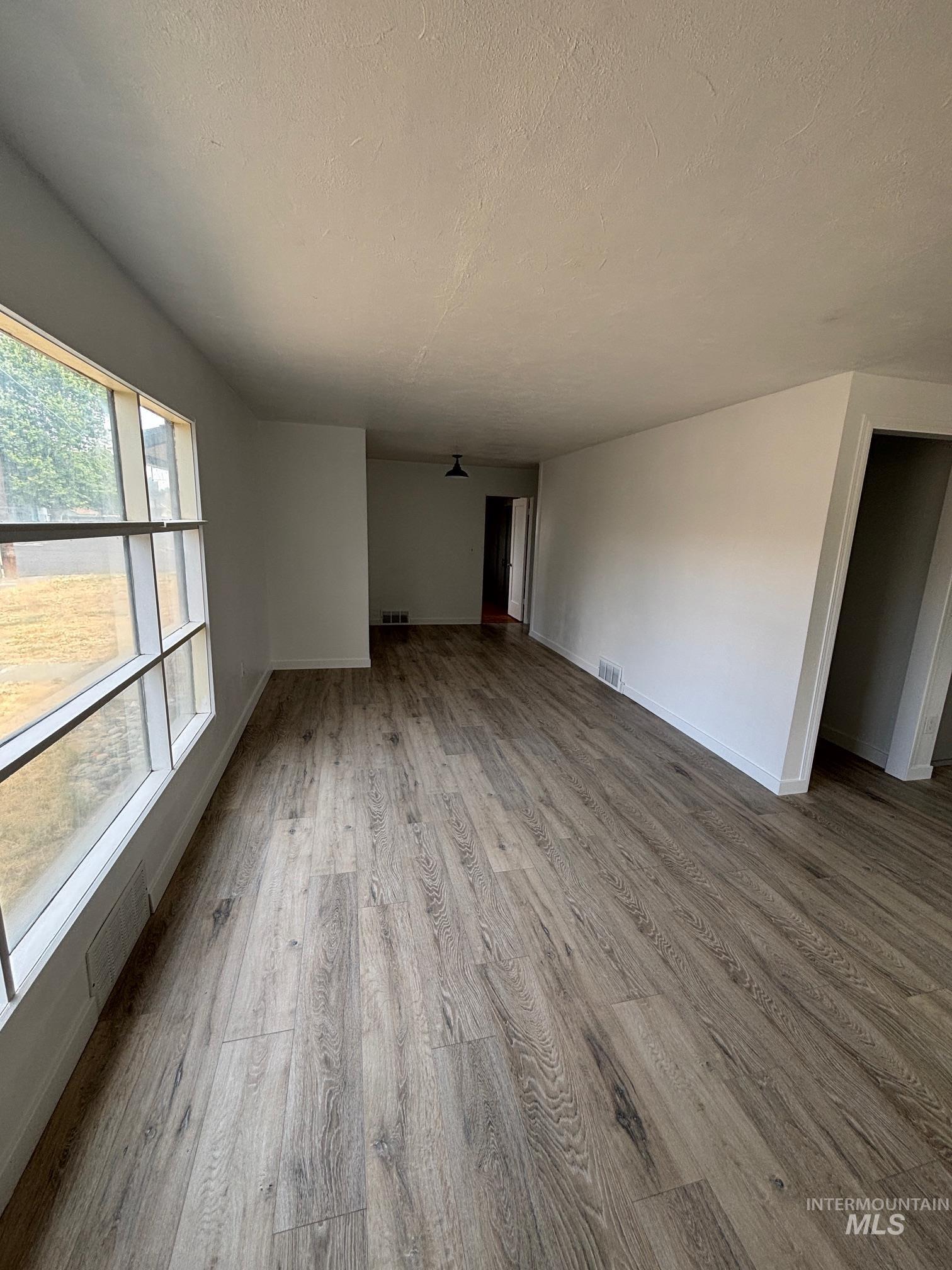 Unfurnished living room featuring wood finished floors and a textured ceiling