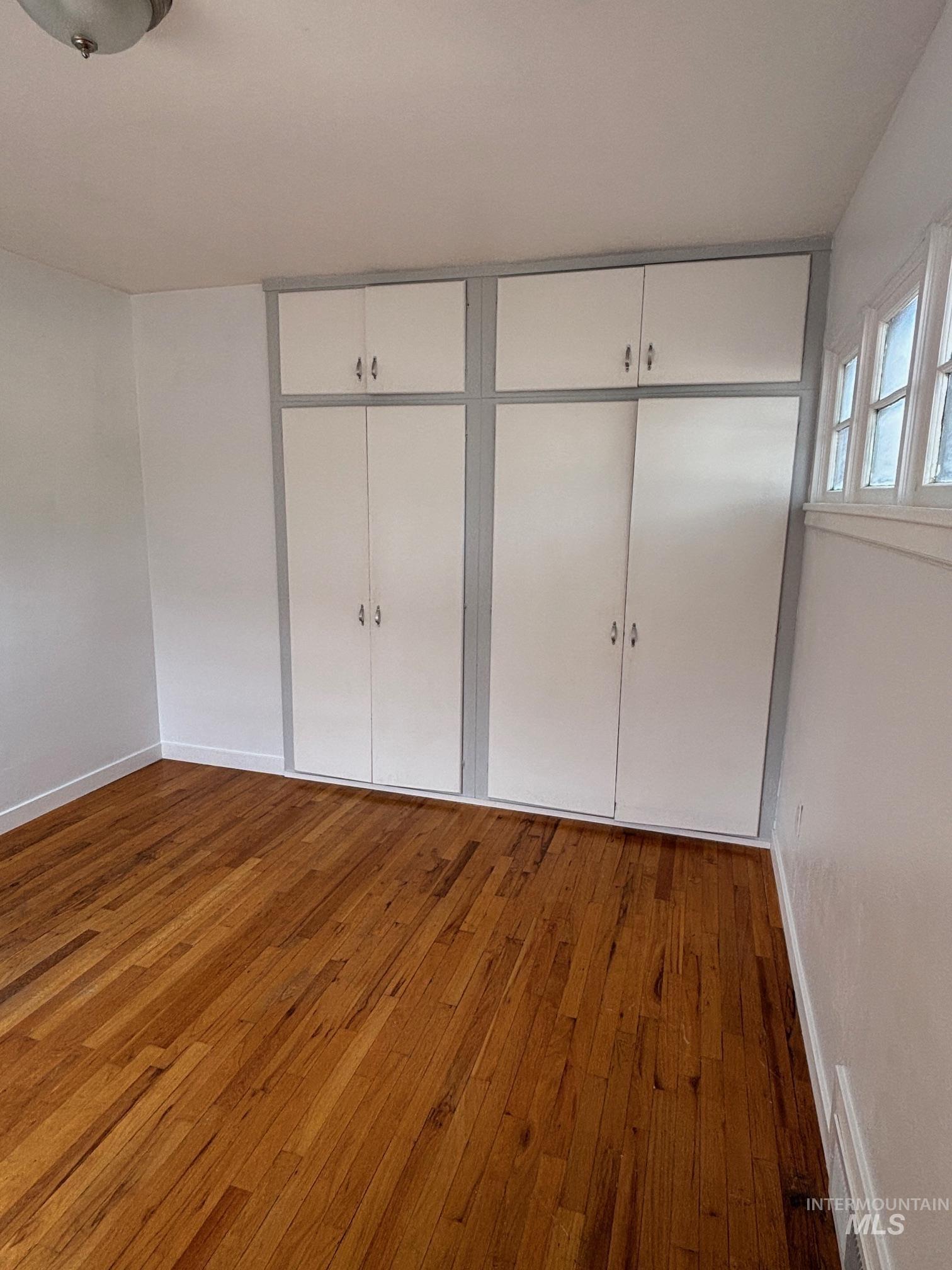 Unfurnished bedroom with wood finished floors and a closet