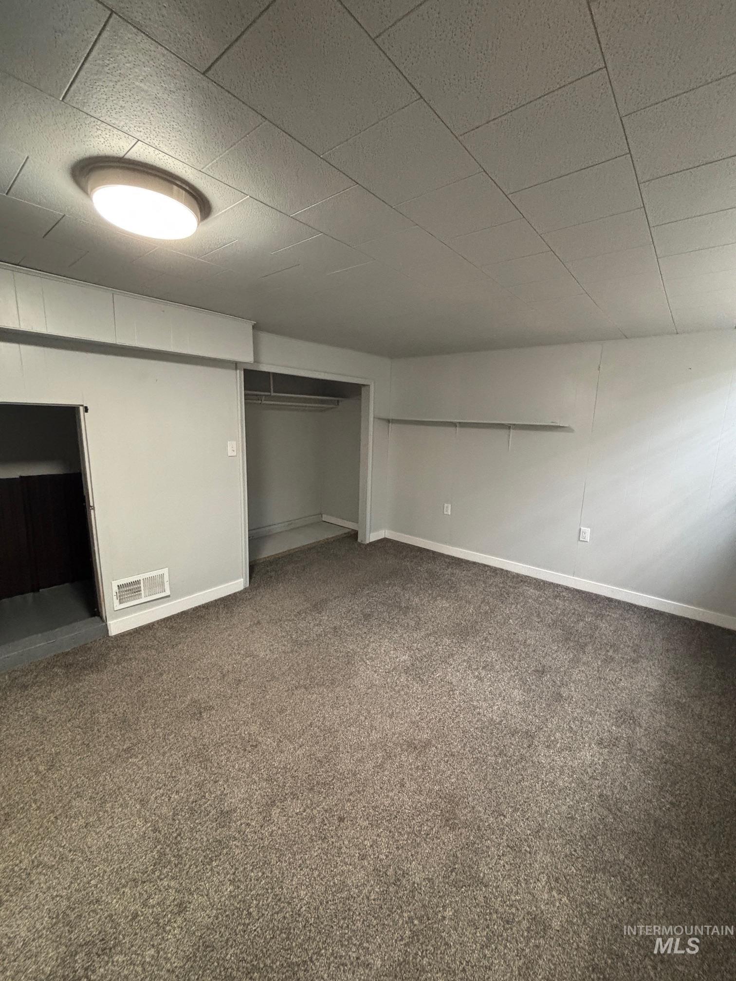 Unfurnished bedroom with dark colored carpet and a closet