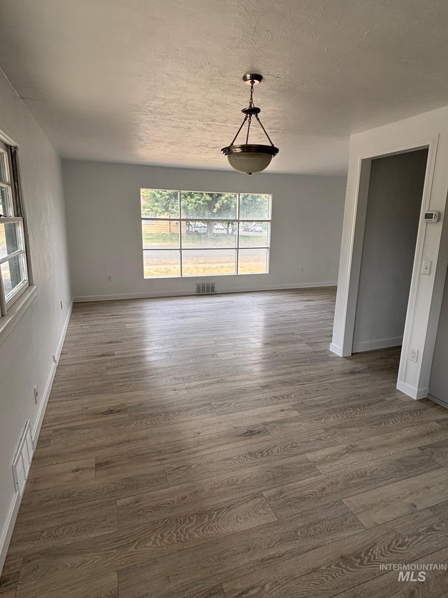 Unfurnished living room with dark wood finished floors and a textured ceiling
