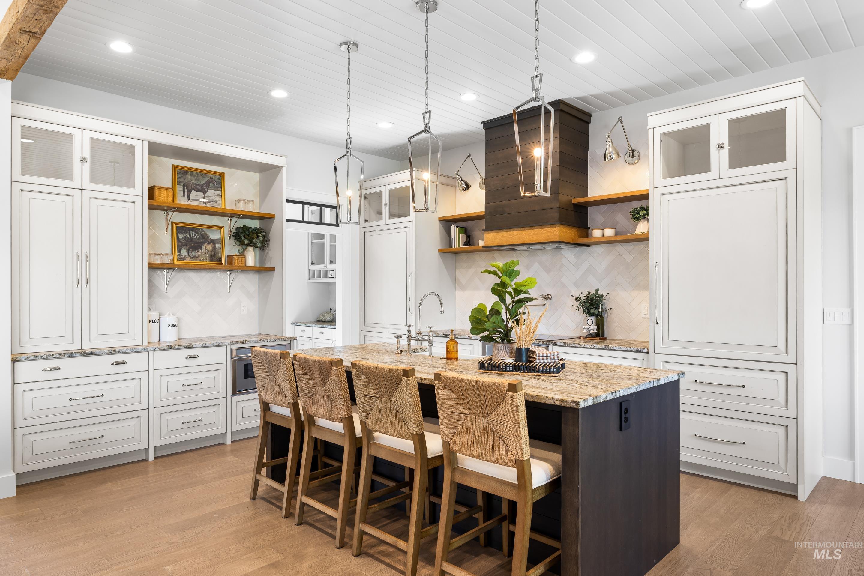 Kitchen with glass insert cabinets, open shelves, light stone countertops, pendant lighting, and recessed lighting