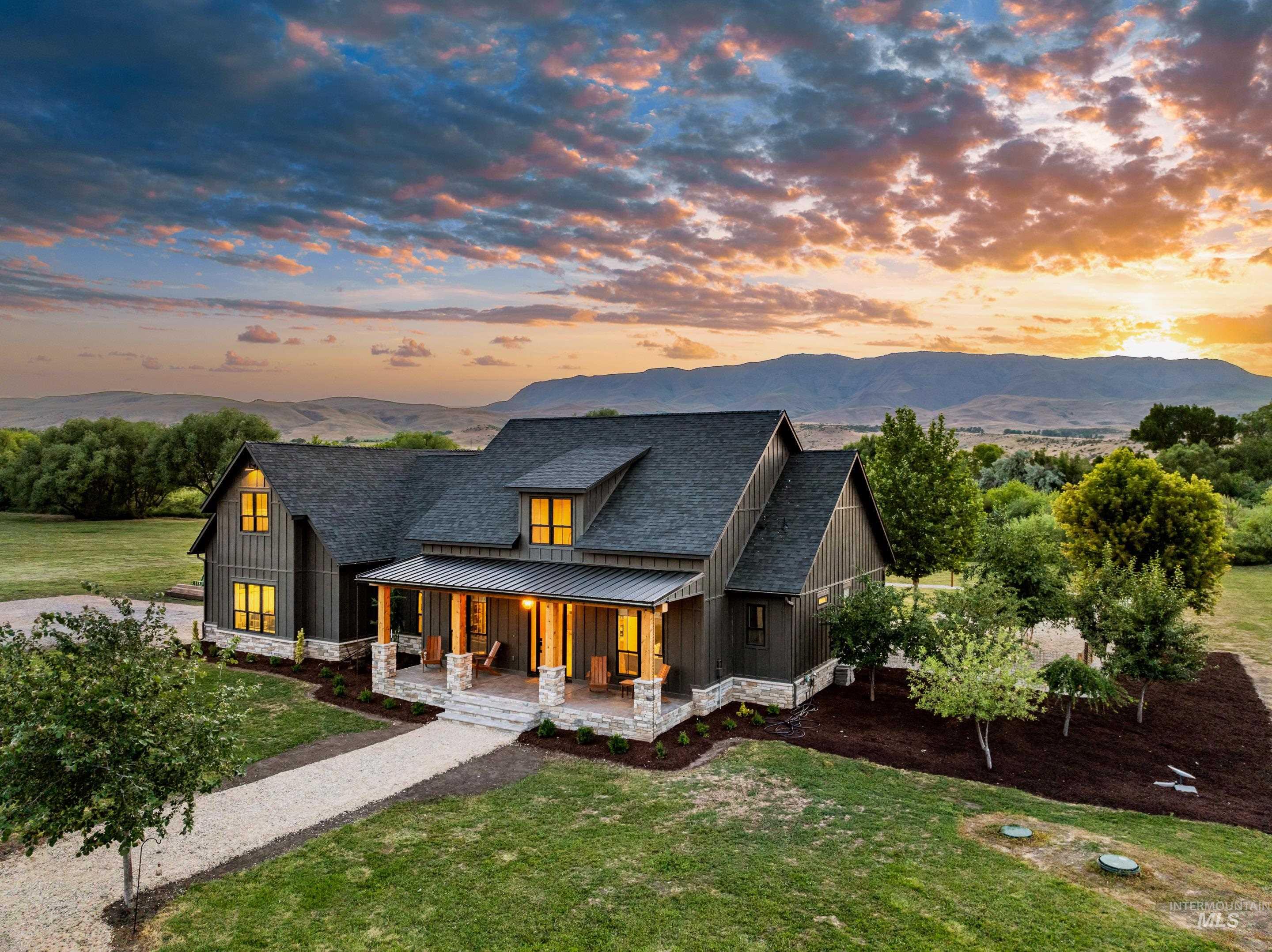 Back of house at dusk with a standing seam roof, a porch, a yard, board and batten siding, and a metal roof