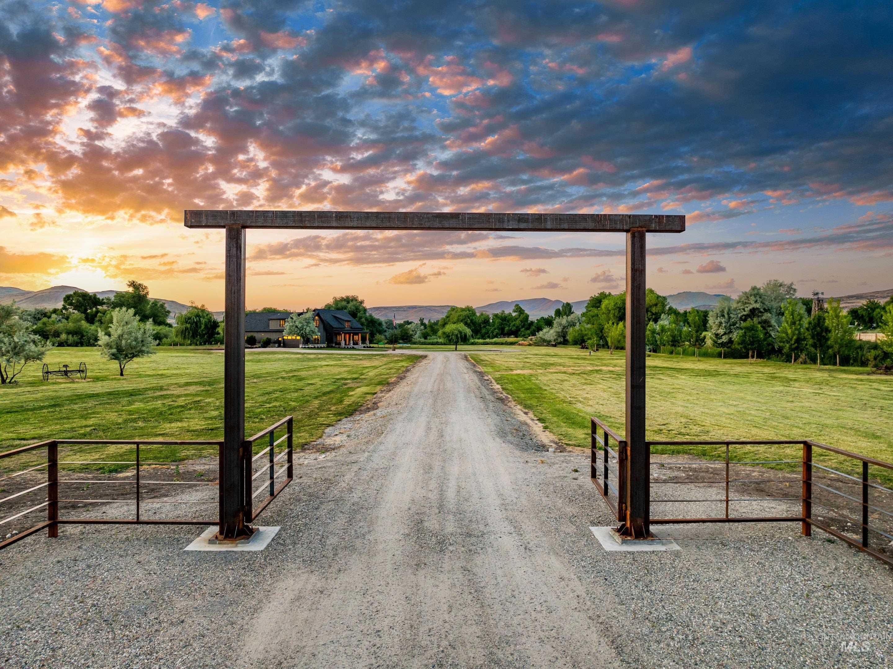 View of dirt / gravel driveway featuring a rural view, a gated entry, and a mountain view