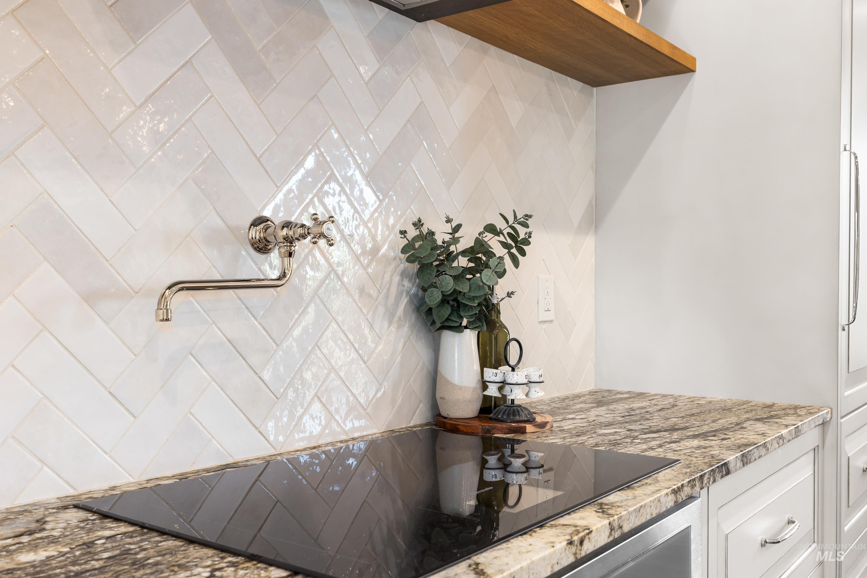 Kitchen with black electric cooktop, light stone counters, and white cabinets
