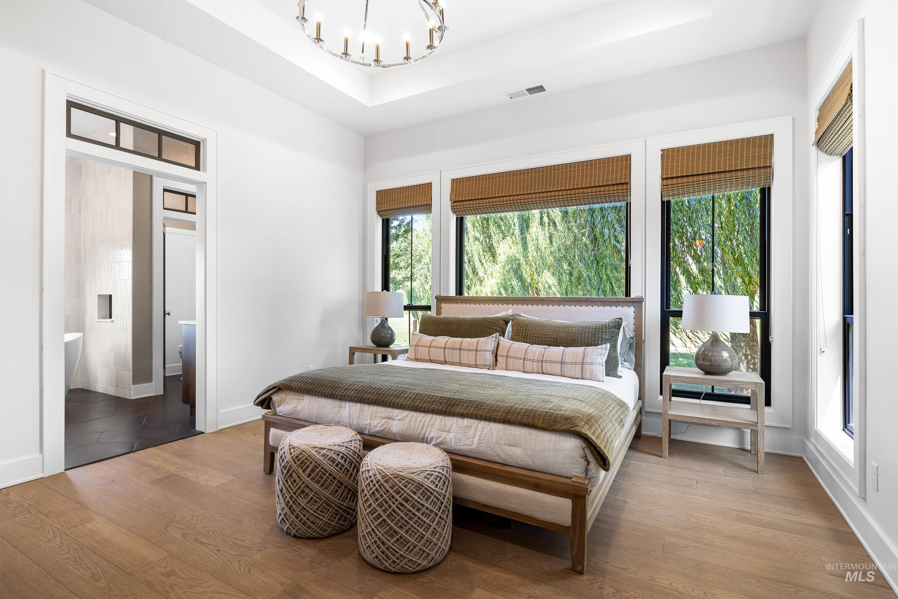 Bedroom featuring wood finished floors, a raised ceiling, and a chandelier