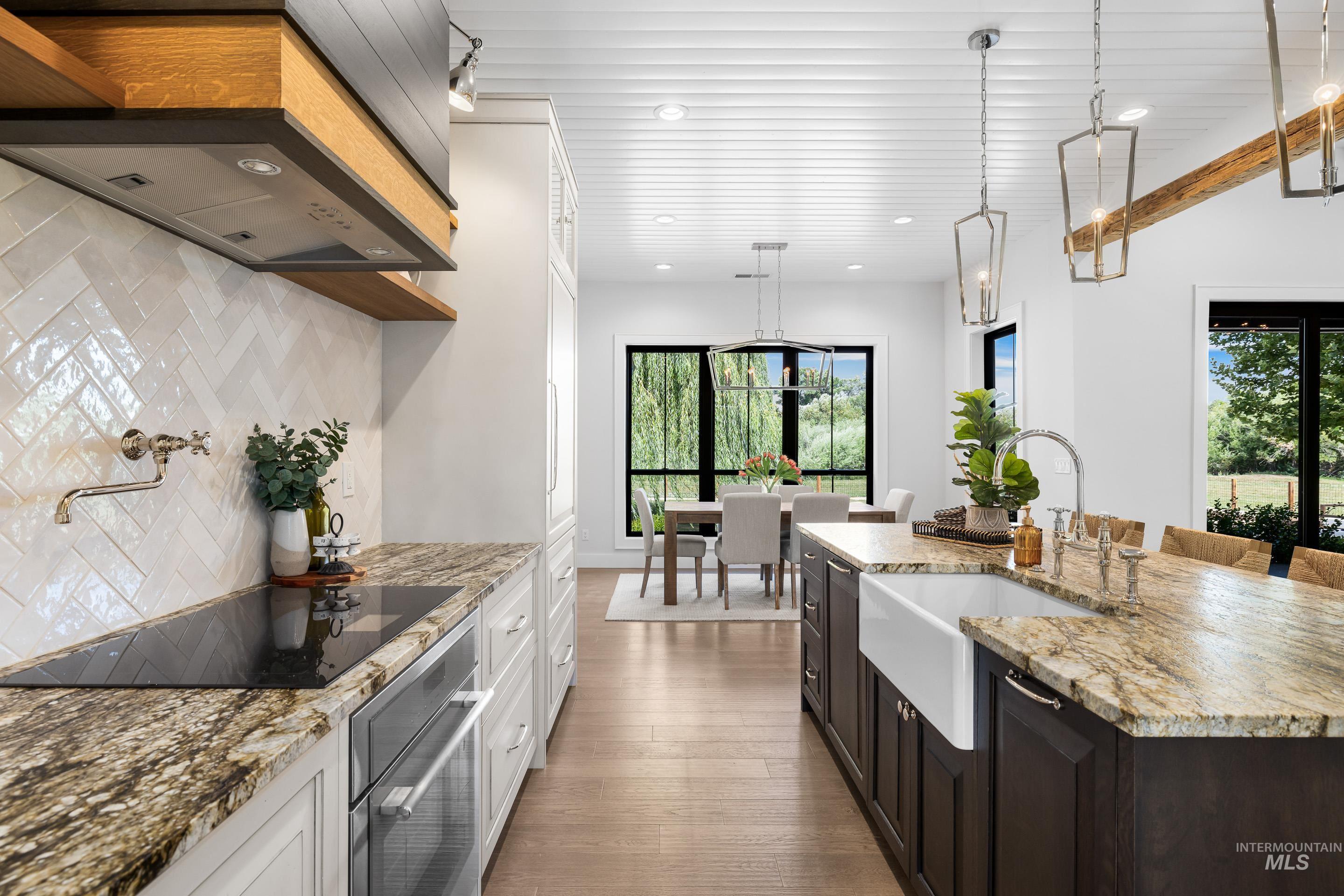 Kitchen with backsplash, light stone counters, plenty of natural light, stainless steel oven, and recessed lighting