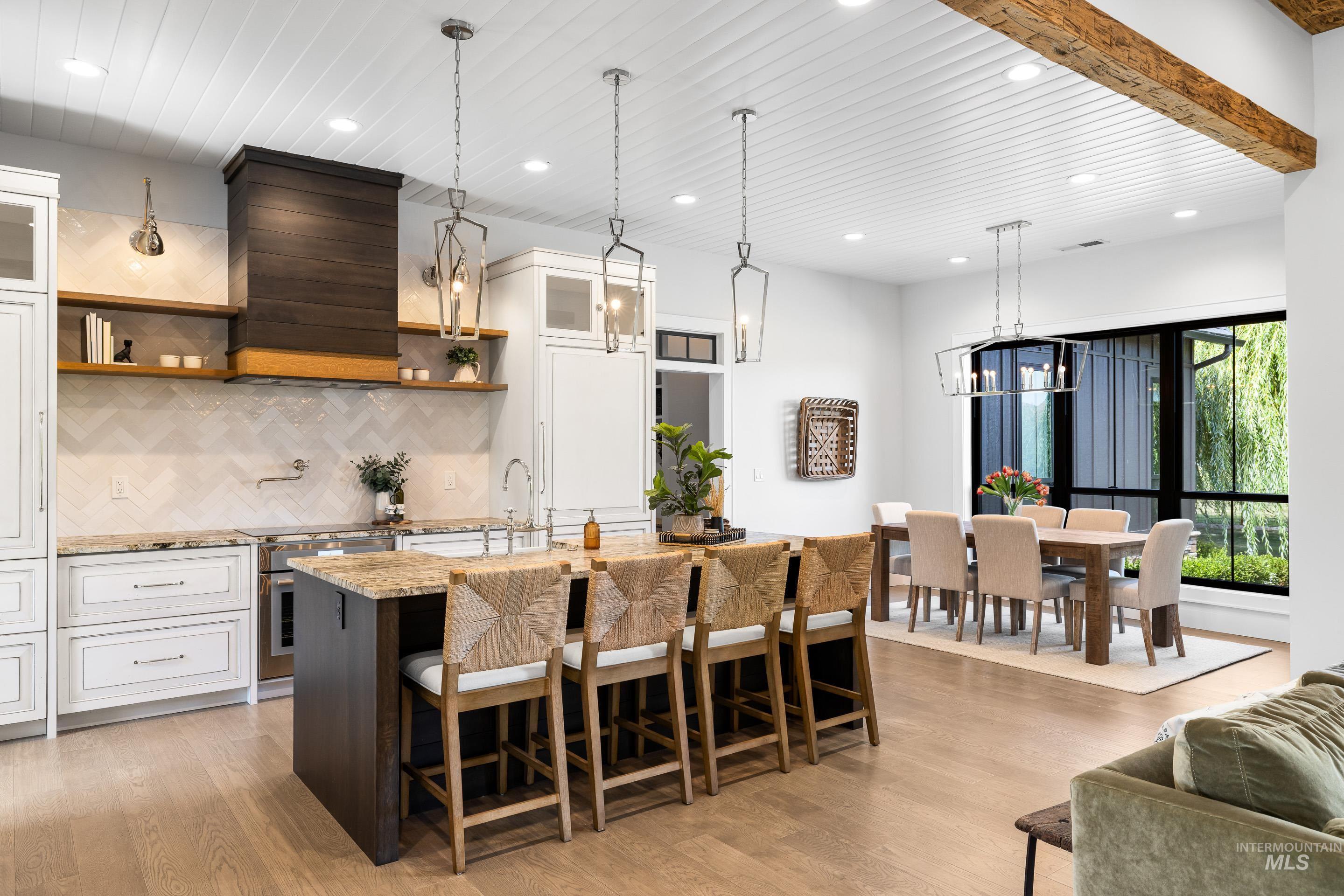 Kitchen featuring glass insert cabinets, a kitchen breakfast bar, white cabinetry, a kitchen island with sink, and recessed lighting