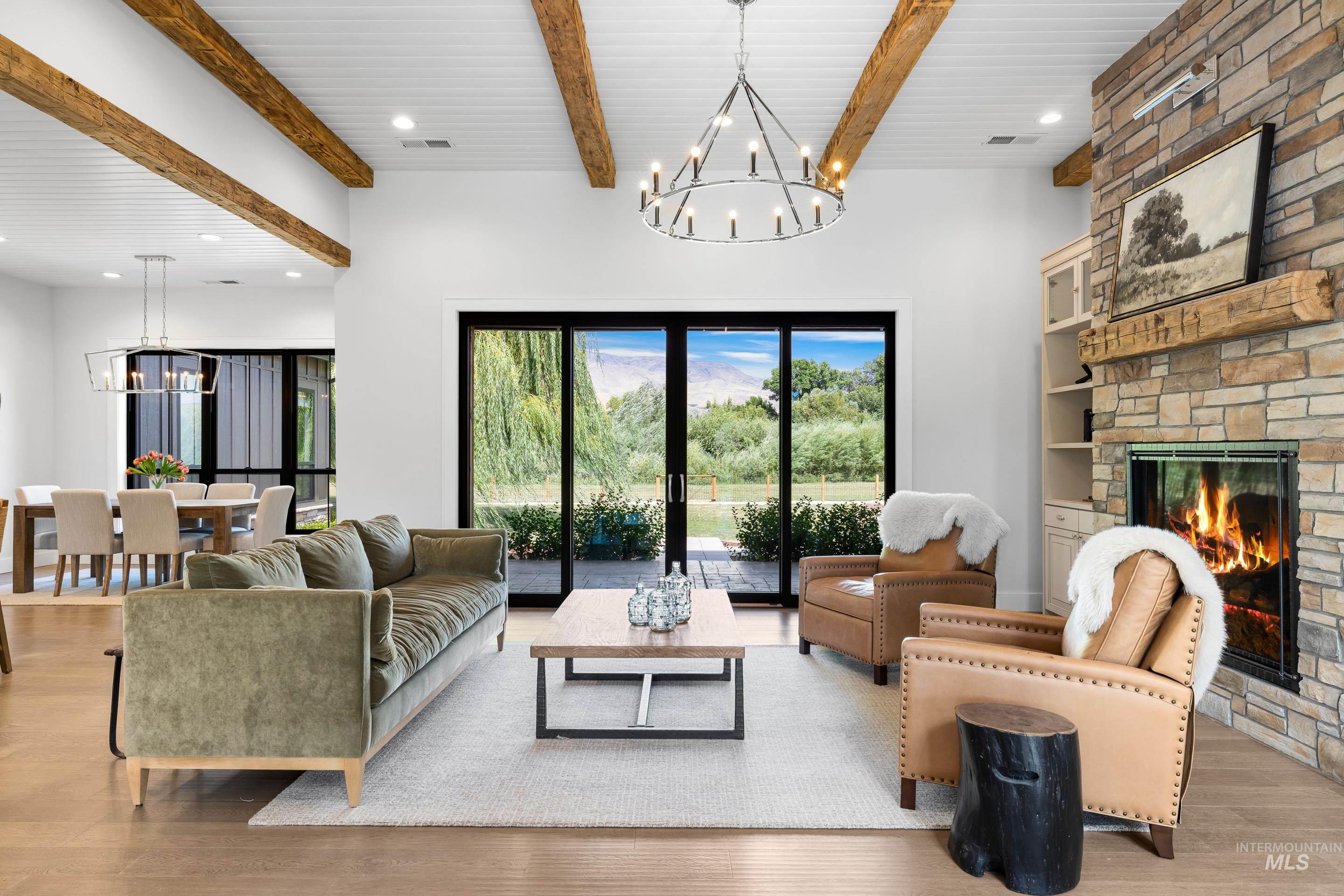 Living room featuring a chandelier, a stone fireplace, wood finished floors, recessed lighting, and beam ceiling