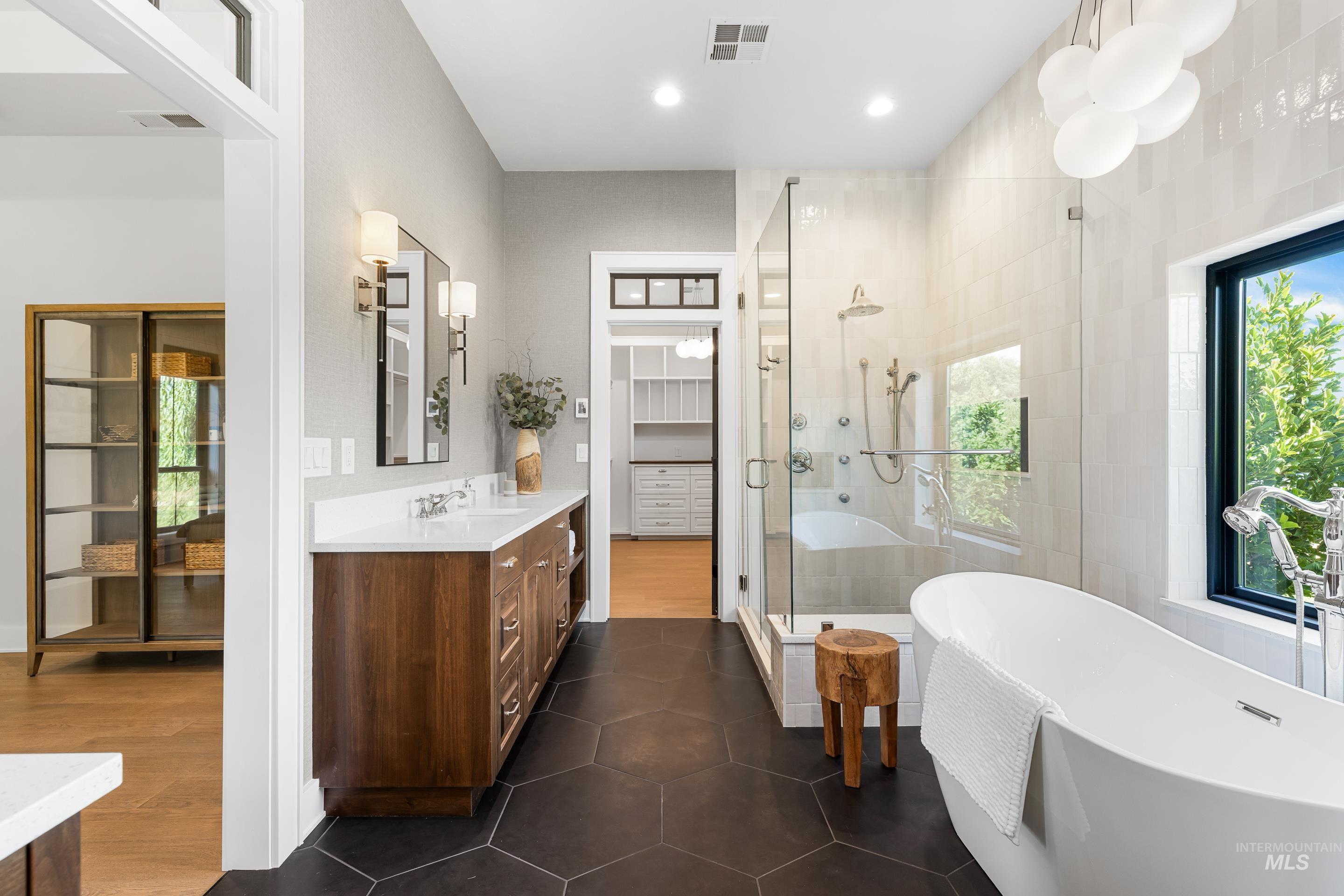 Full bathroom with a shower stall, a freestanding bath, vanity, dark tile patterned flooring, and recessed lighting