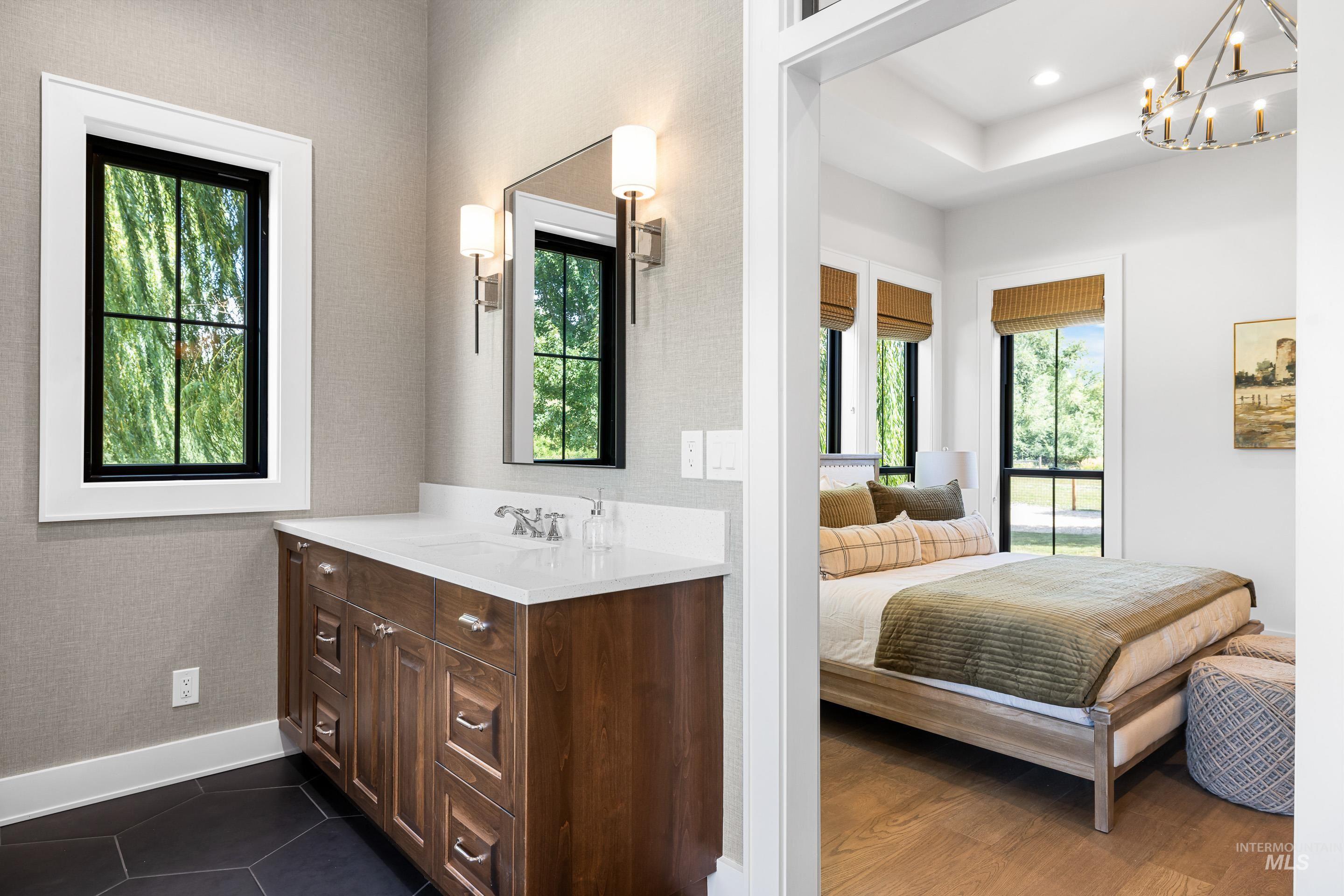 Bathroom with vanity, ensuite bath, a chandelier, and dark tile patterned floors