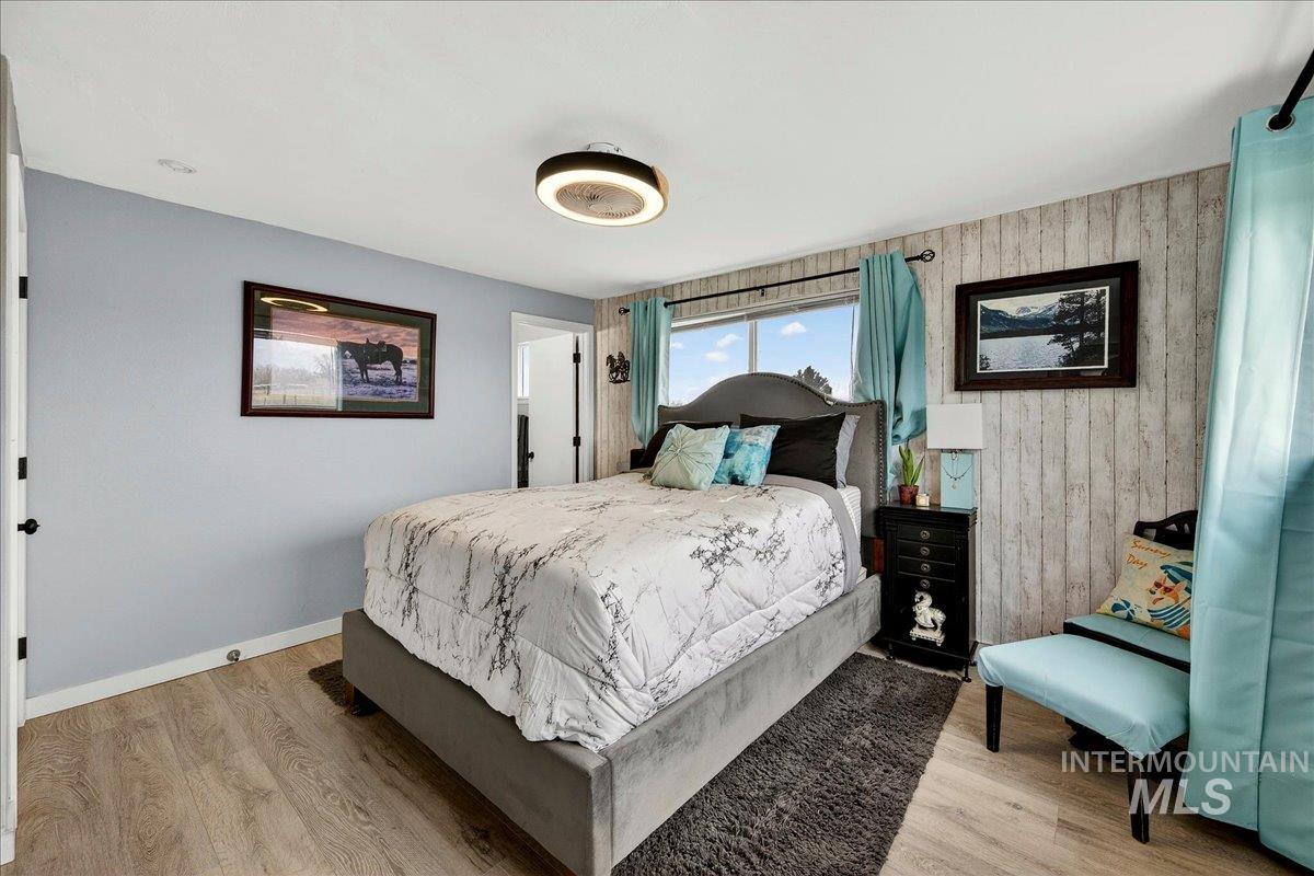 Bedroom with light wood-type flooring and wood walls