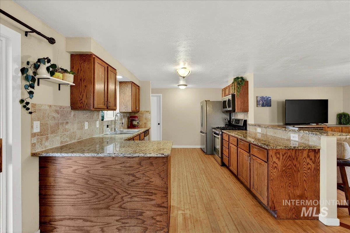 Kitchen featuring a peninsula, wood finish cabinets, and light stone countertops