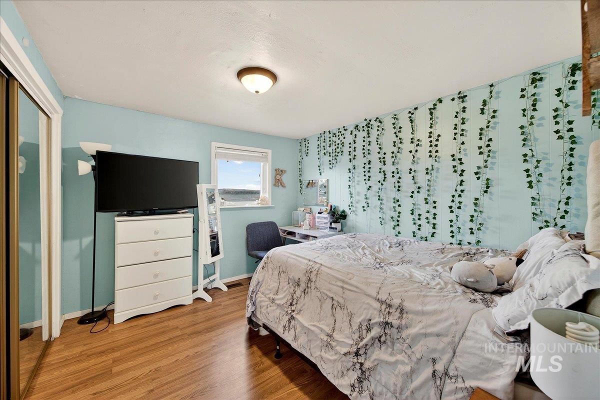 Bedroom with light wood finished floors, wallpapered walls, a closet, and an accent wall