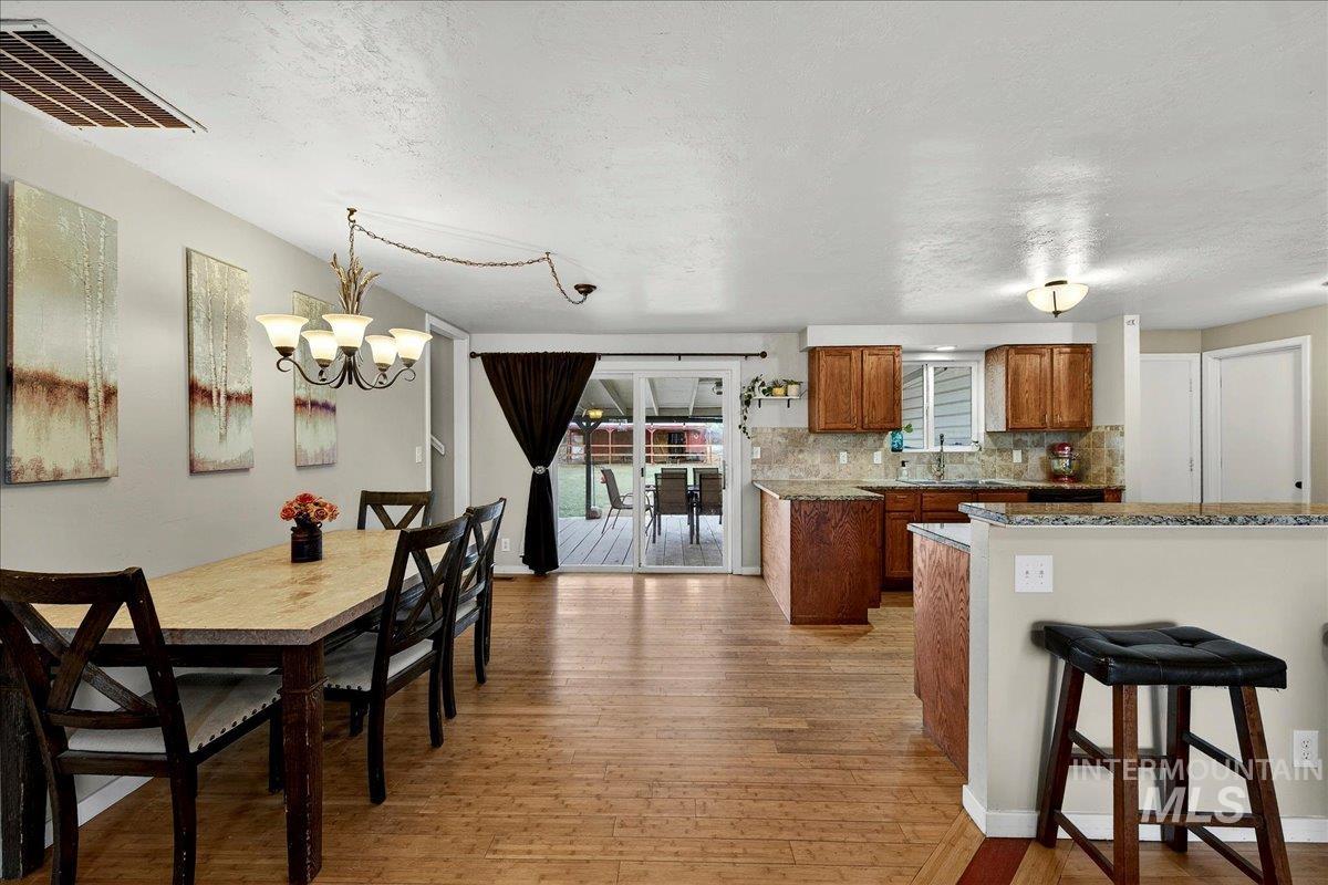 Dining space with light wood-style flooring, hanging lights, and a textured ceiling