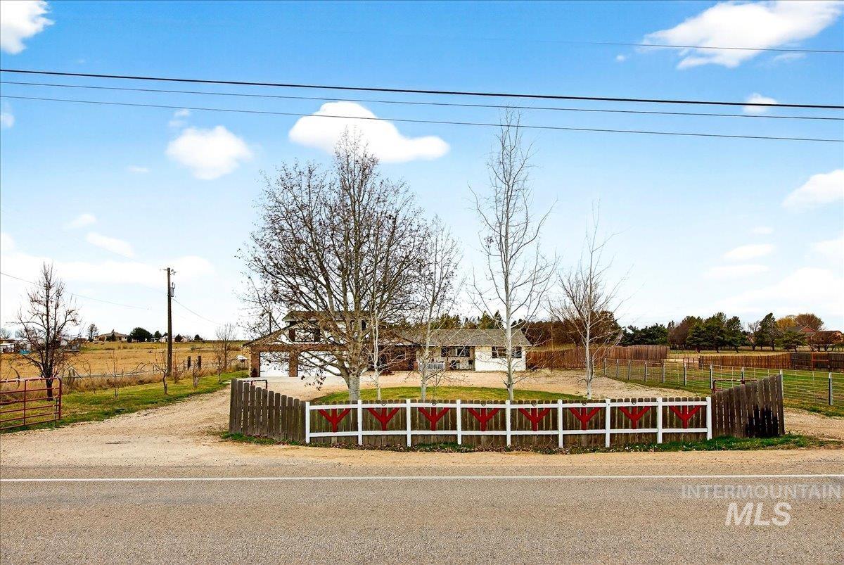 View of front facade with a fenced front yard and a rural view