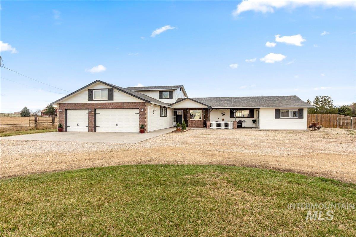 View of front facade with driveway, a porch, and brick siding