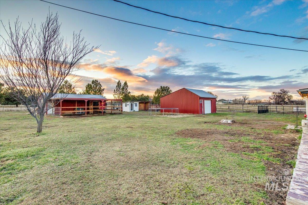 Yard at dusk featuring an outdoor structure and a garage