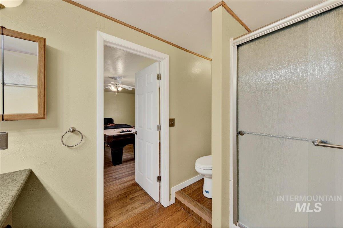 Full bathroom with light wood-type flooring, a stall shower, vanity, ceiling fan, and a textured wall
