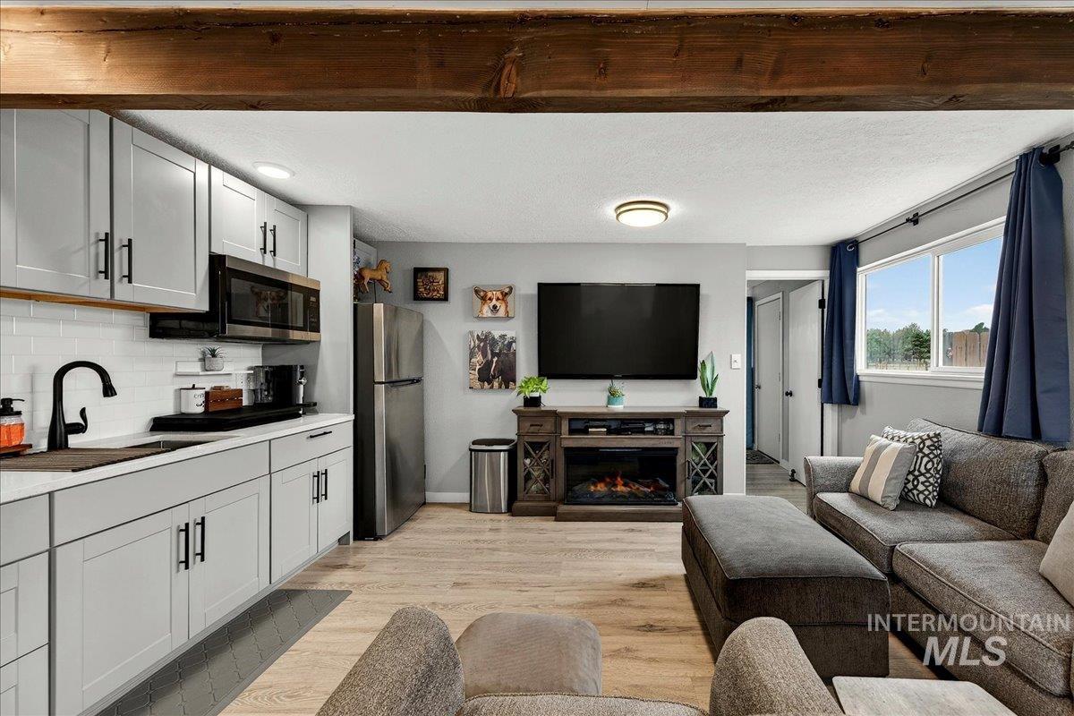 Living area with light wood-style floors, a glass covered fireplace, and a textured ceiling