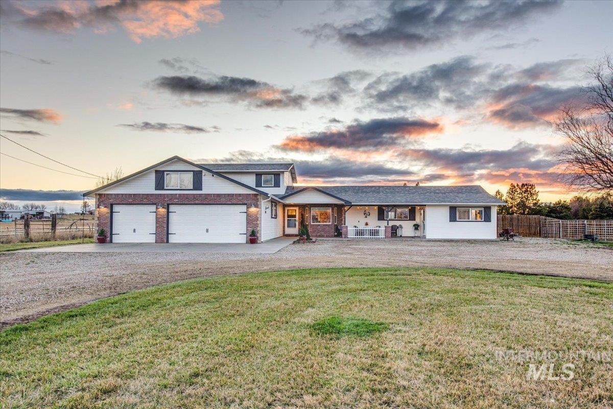 View of front of home featuring driveway, covered porch, and brick siding