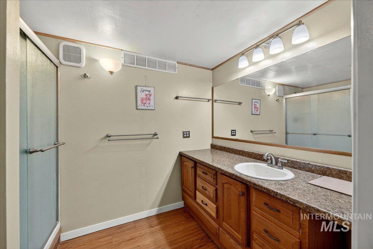 Bathroom featuring a stall shower, vanity, and light wood-style flooring