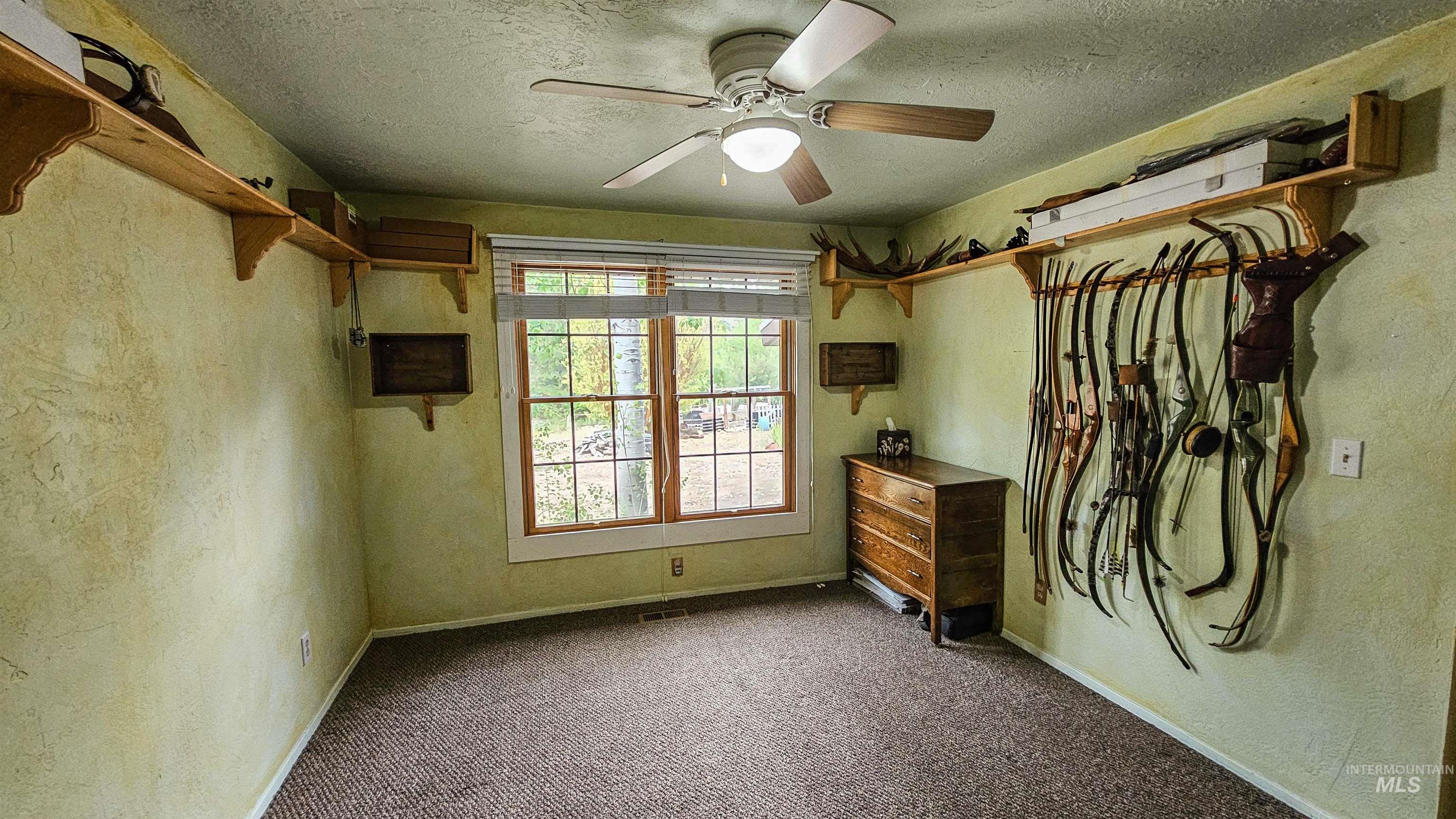 Unfurnished bedroom featuring carpet flooring, a textured ceiling, ceiling fan, and a textured wall