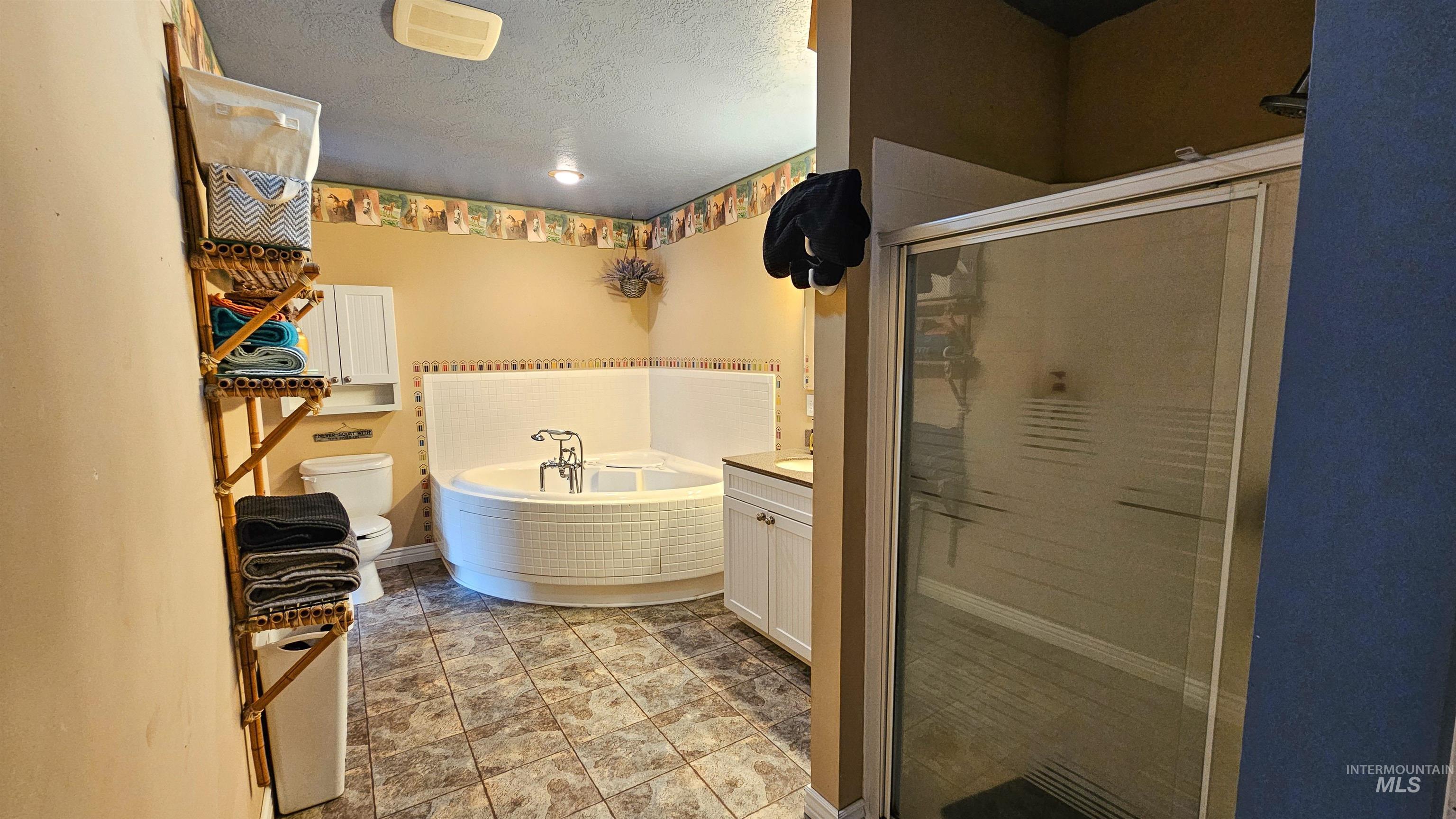 Full bathroom featuring a shower stall, a bath, vanity, and a textured ceiling