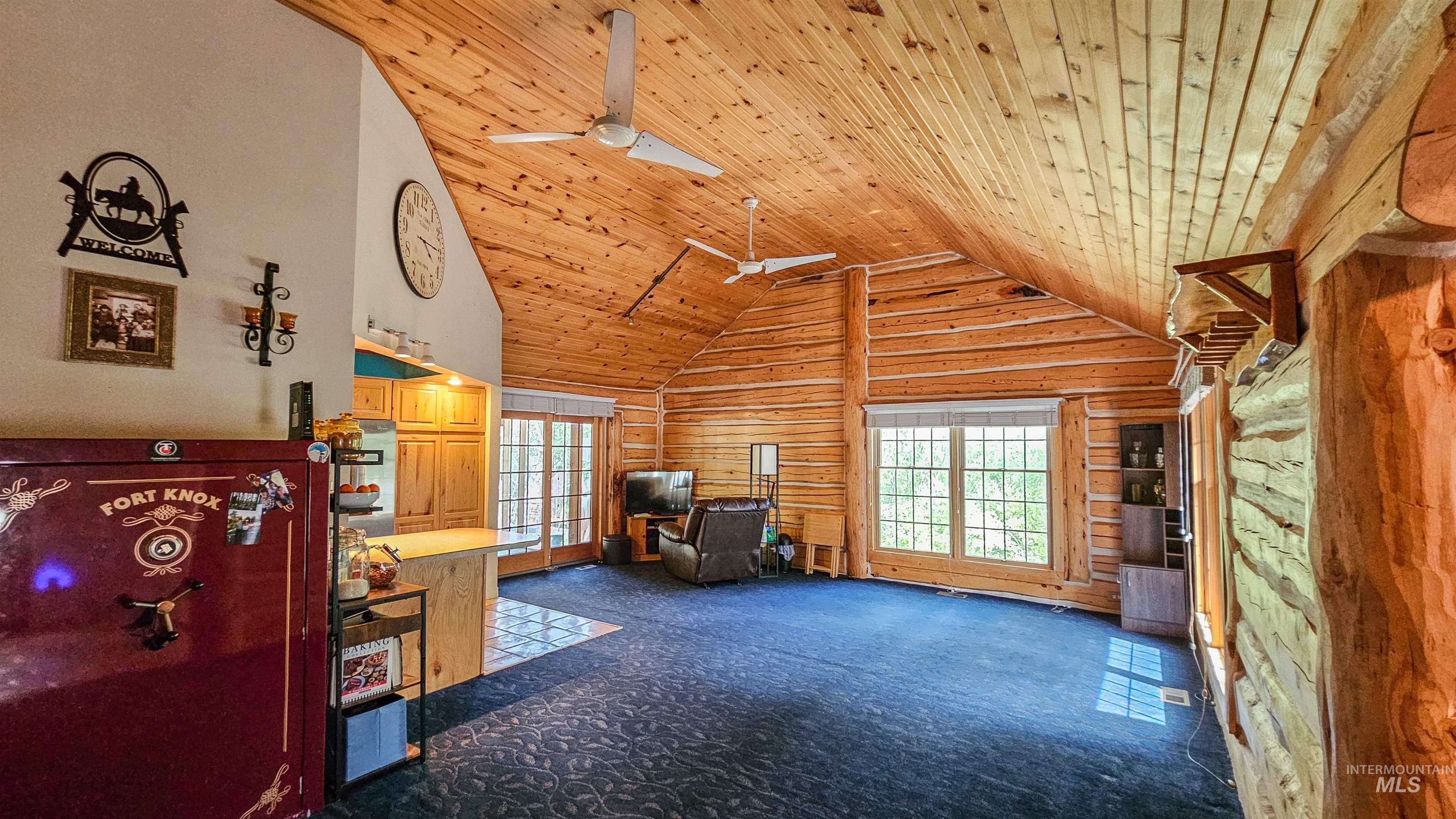 Carpeted living room with wooden ceiling, wooden walls, ceiling fan, high vaulted ceiling, and french doors