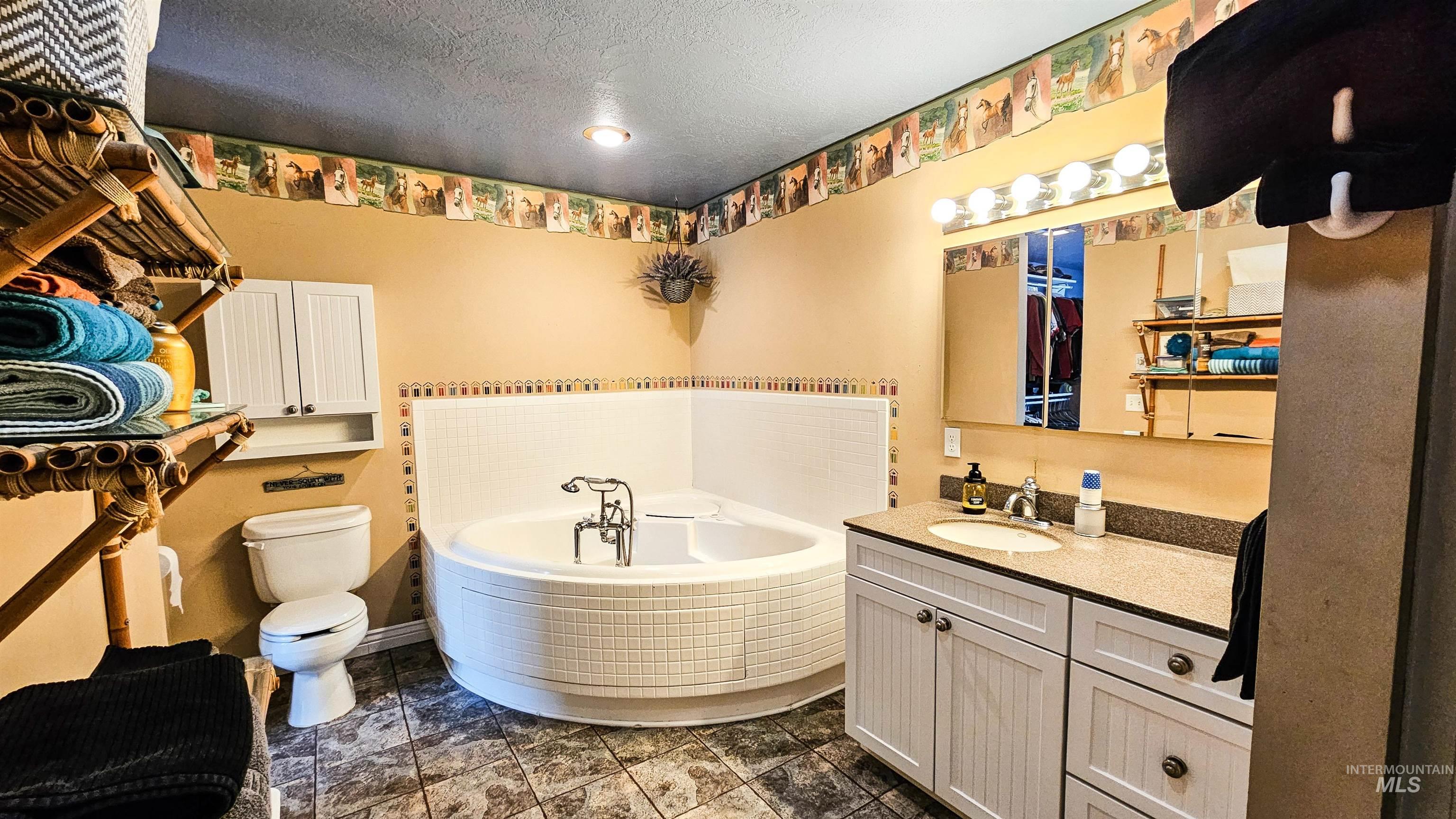 Full bath featuring vanity, a garden tub, and a textured ceiling