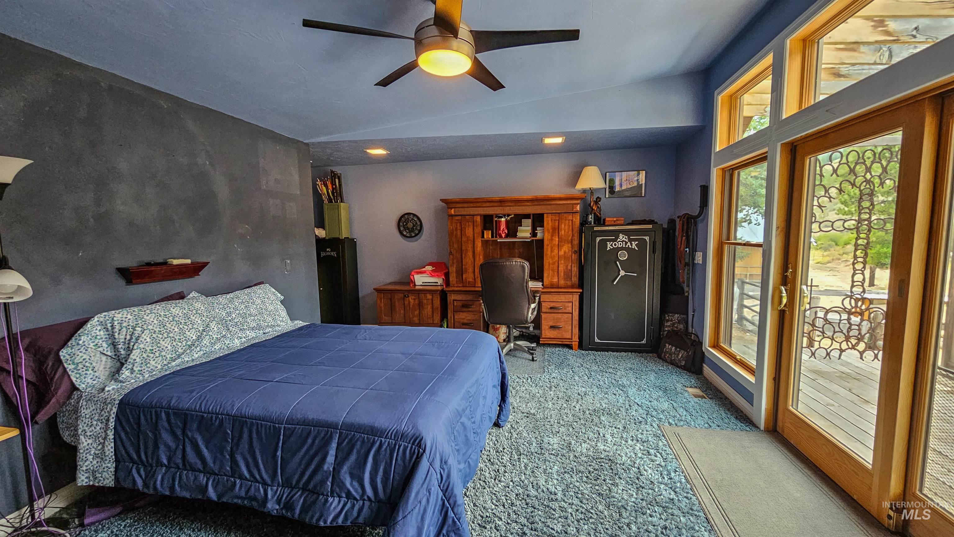 Bedroom featuring an office area, carpet floors, vaulted ceiling, access to outside, and ceiling fan