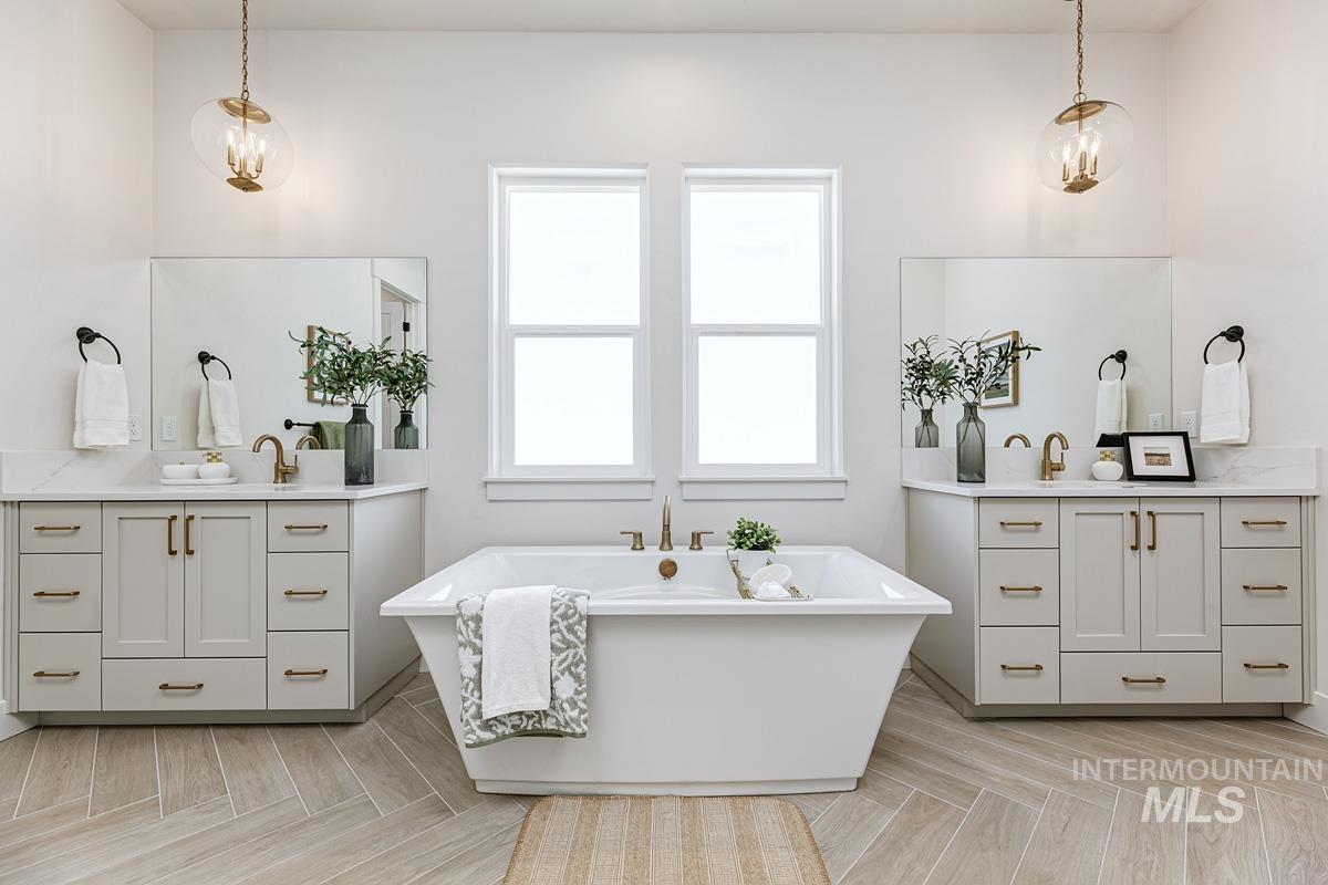 Full bath with two vanities, a freestanding tub, and a chandelier