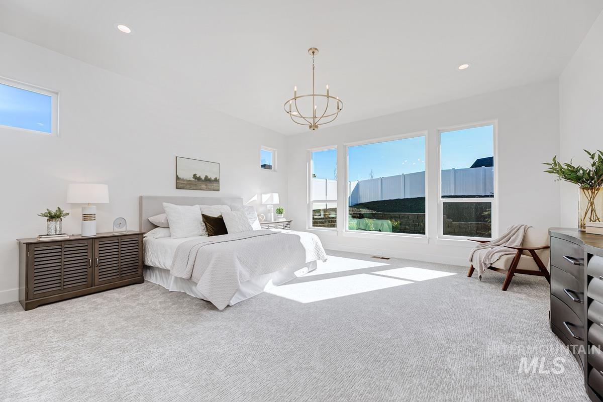 Carpeted bedroom with multiple windows, recessed lighting, and a chandelier