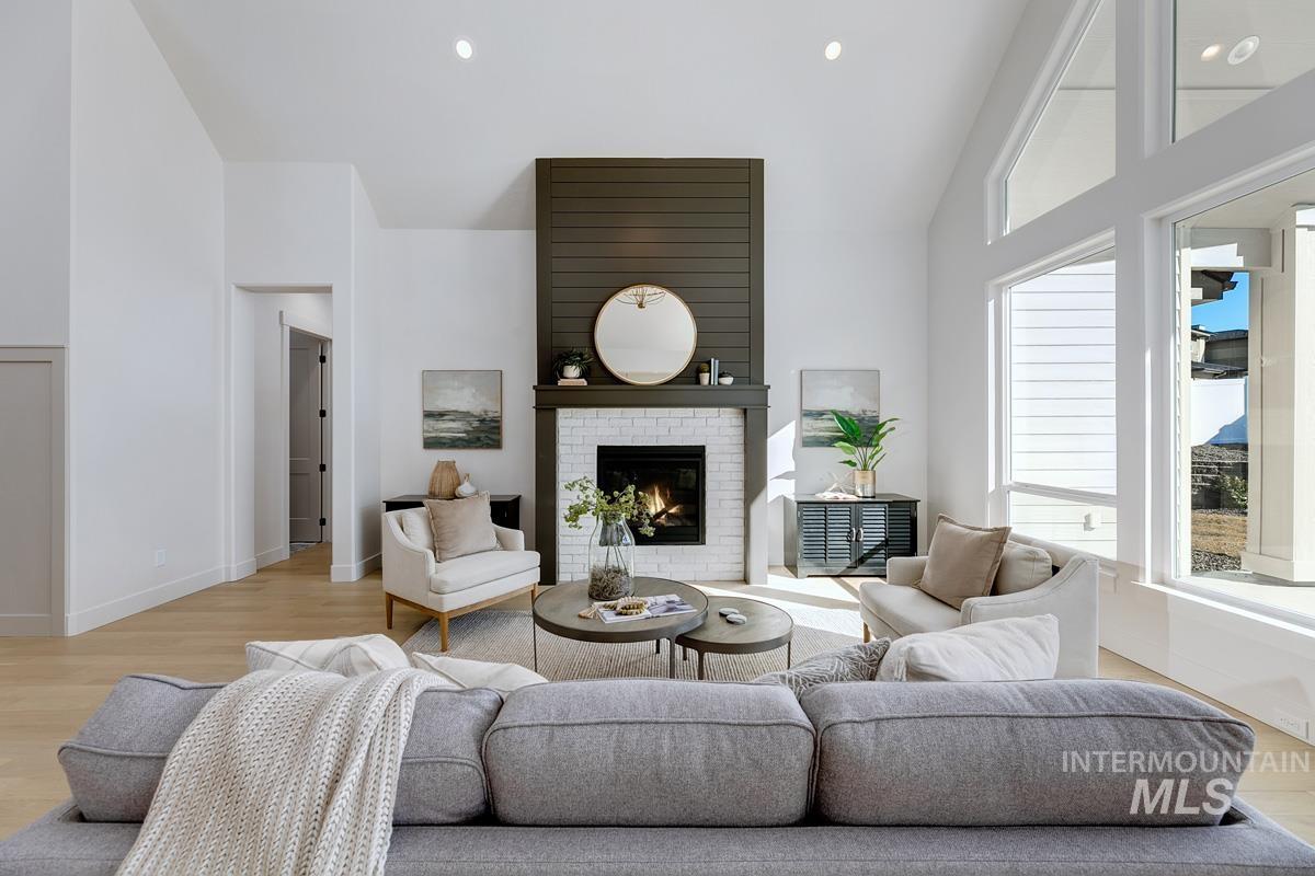 Living area with light wood finished floors, high vaulted ceiling, a fireplace, and recessed lighting