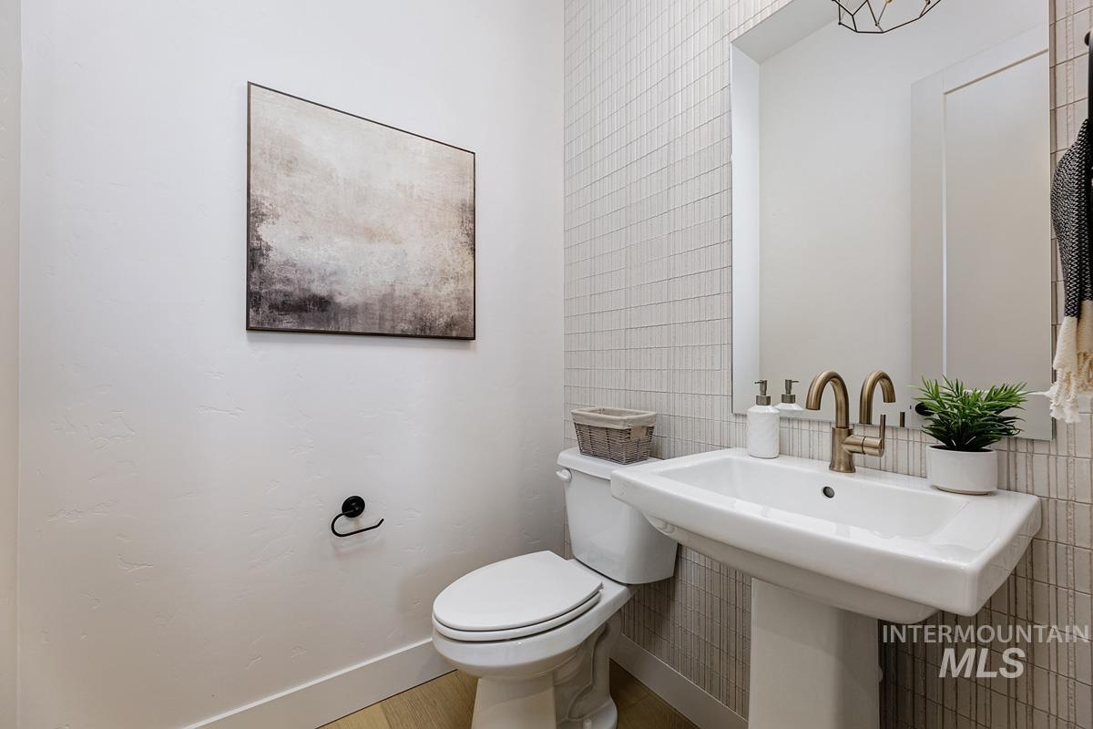 Half bathroom featuring tile walls and toilet